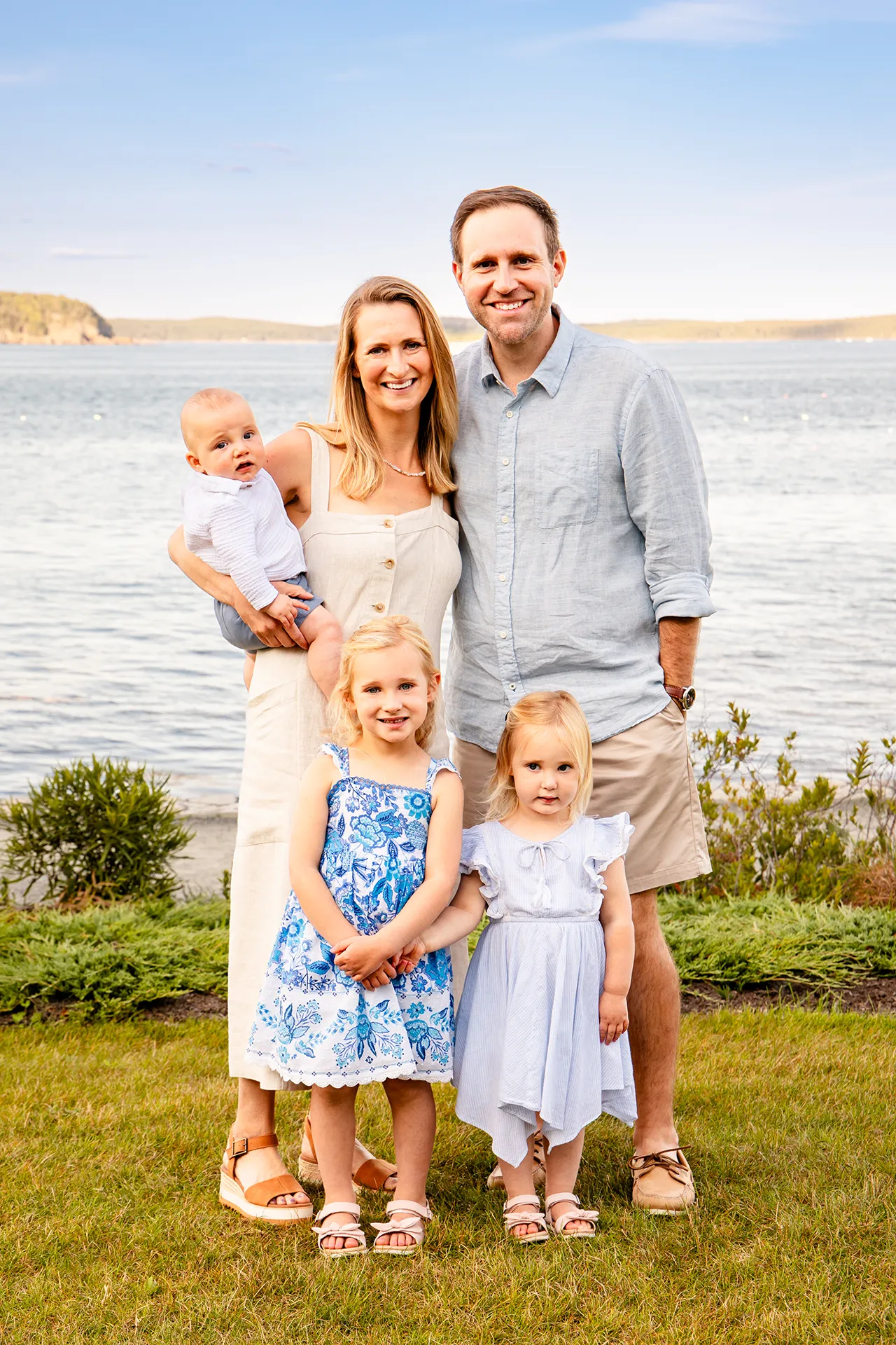 A family smiles and poses in front of Frenchman Bay during a portrait session at the Bar Harbor Inn & Spa in Bar Harbor, Maine.