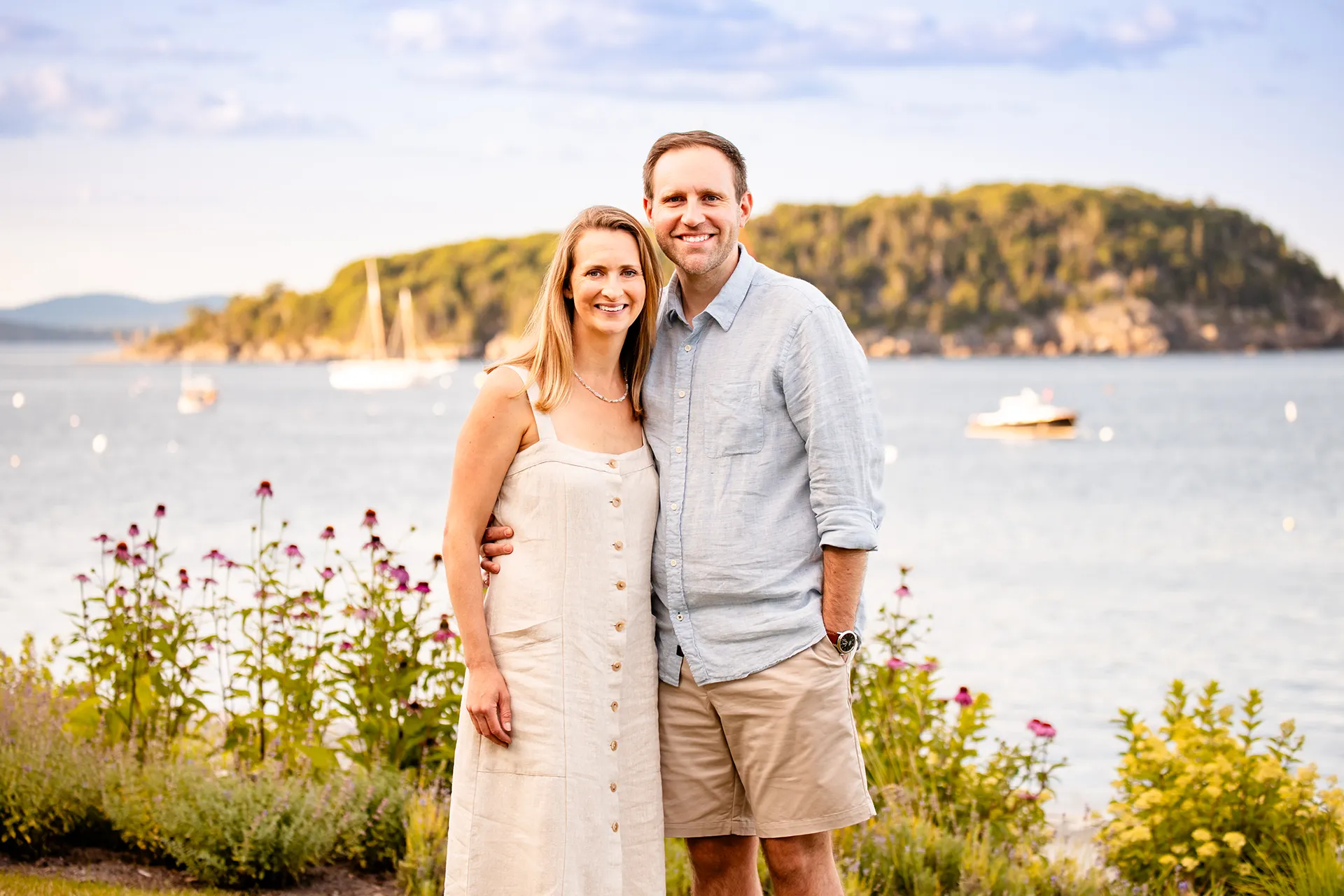 A married couple smile and pose in front of Bar Island during a portrait session at the Bar Harbor Inn & Spa in Bar Harbor, Maine.