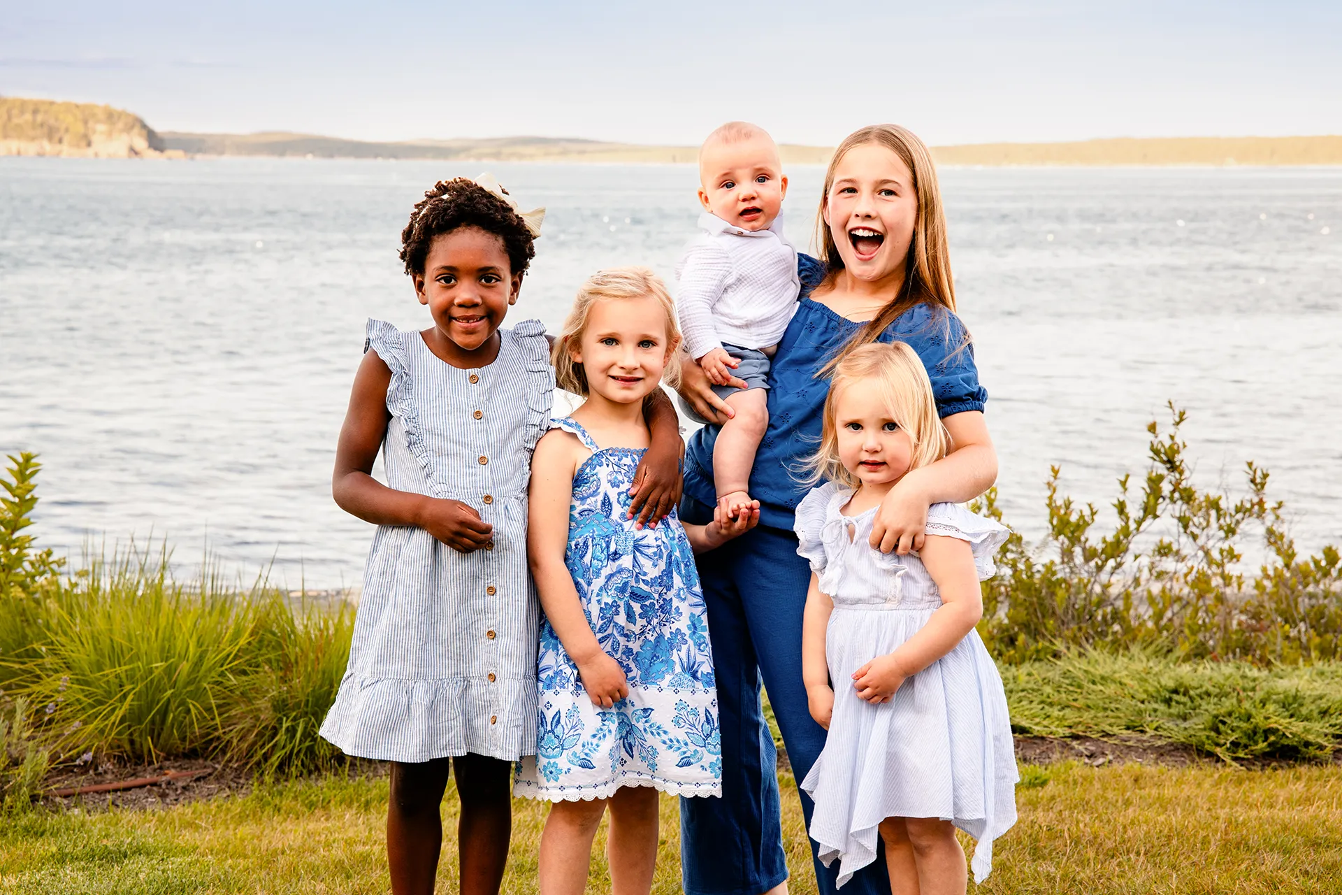 Children smile and pose in front of Frenchman Bay during a portrait session at the Bar Harbor Inn & Spa in Bar Harbor, Maine.