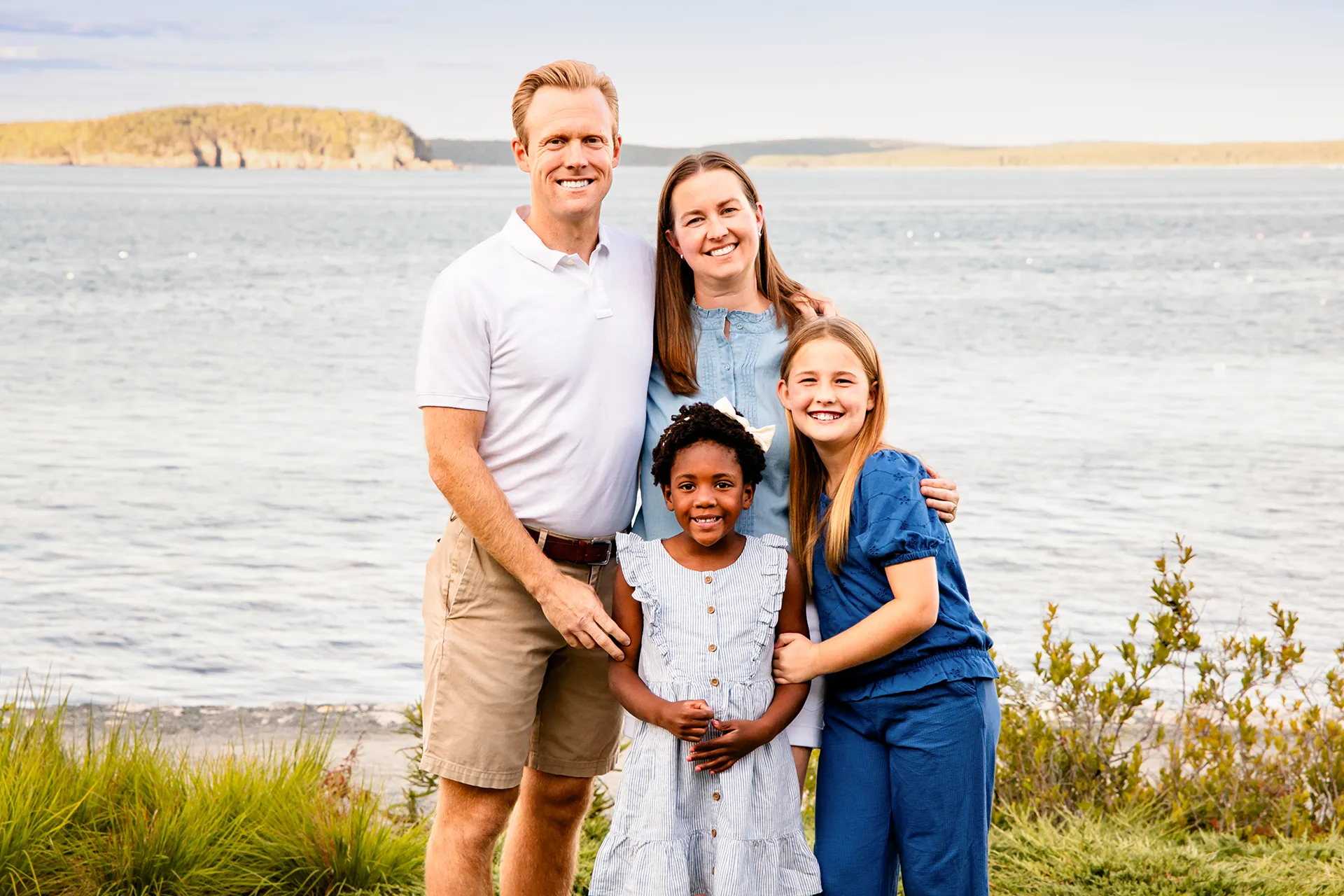 A family smiles and poses during a portrait session in front of Bar Island at the Bar Harbor Inn & Spa in Bar Harbor, Maine.