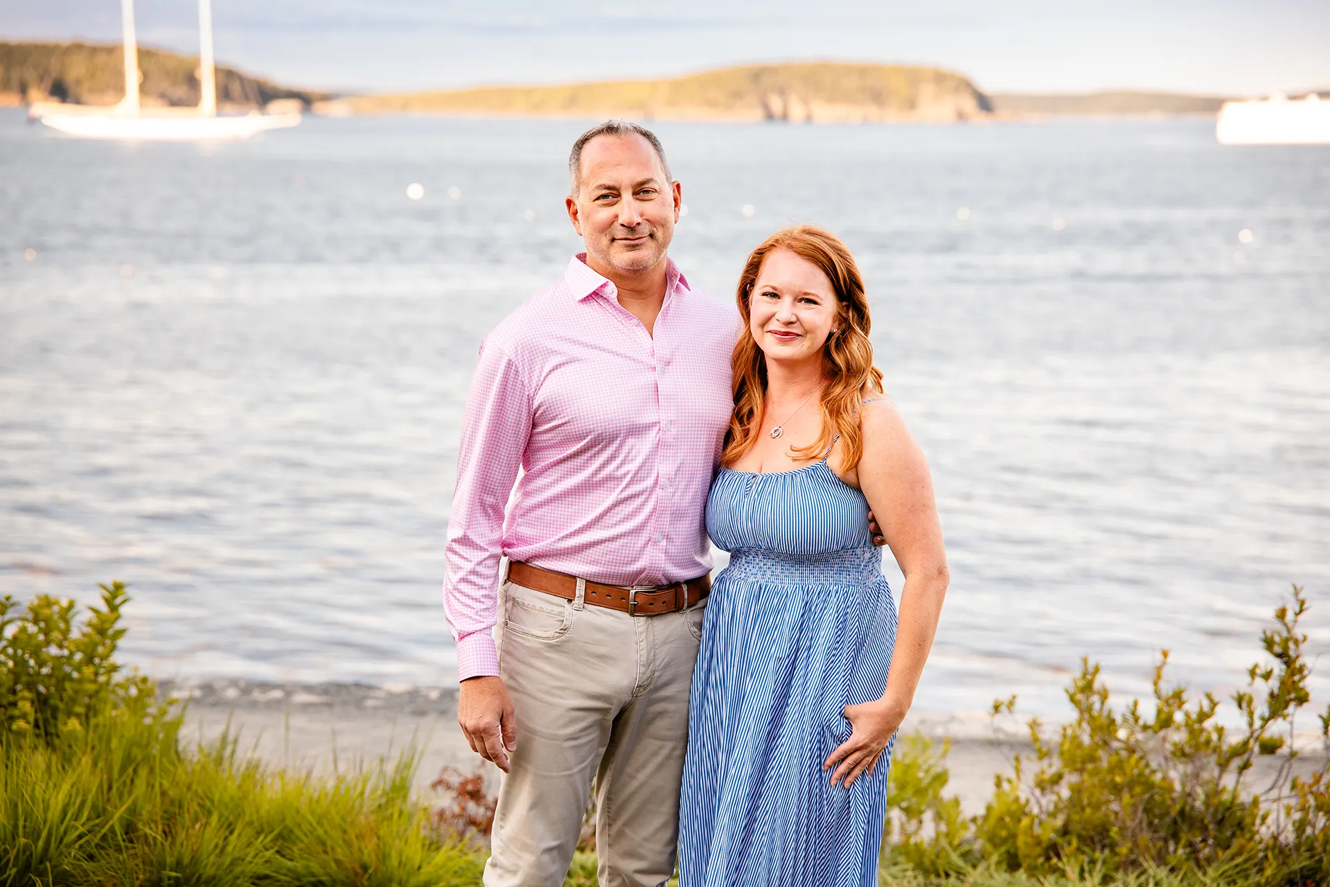 A man and woman pose for portraits in front of Frenchmen Bay at the Bar Harbor Inn & Spa in Bar Harbor, Maine.