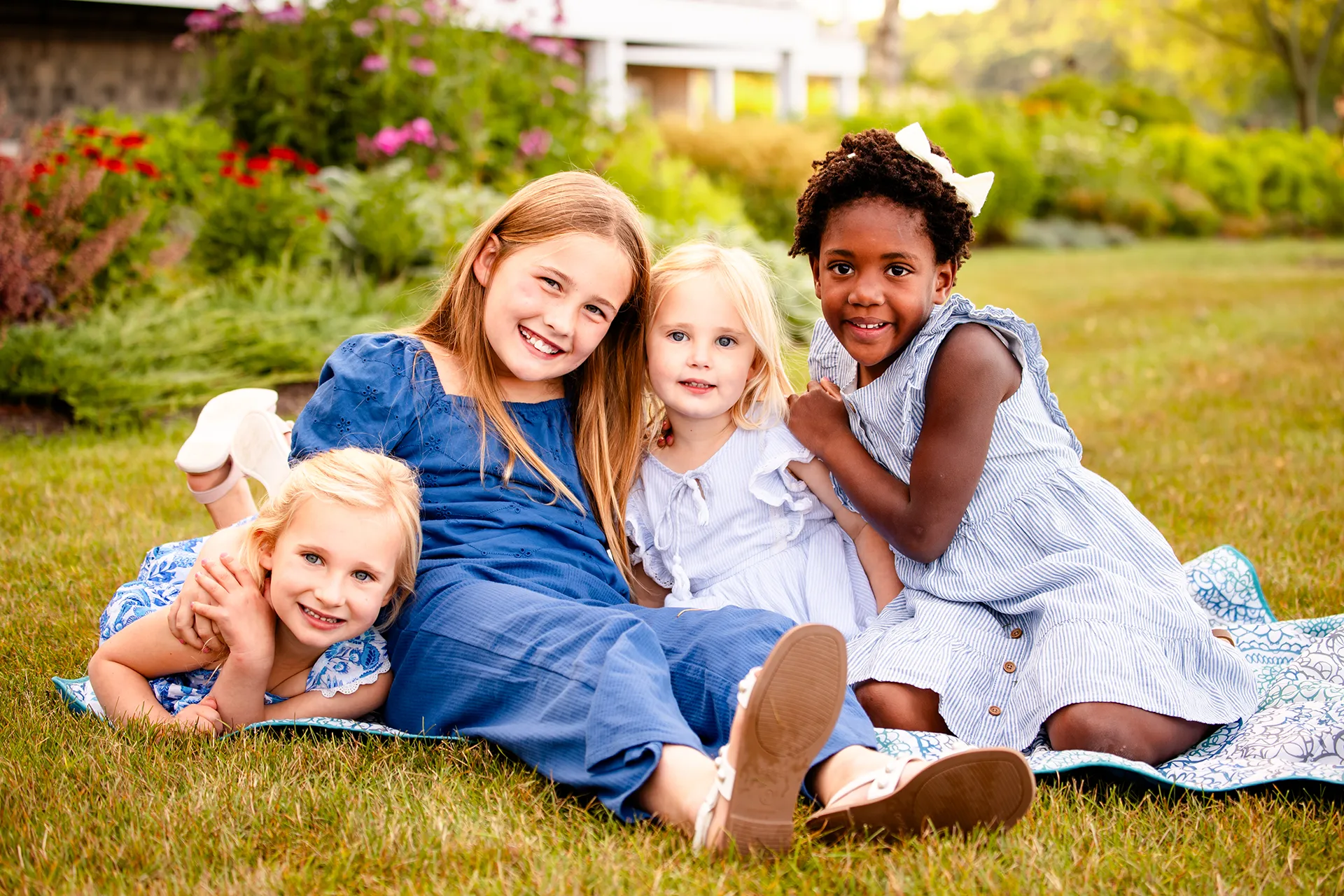 Four young girls sit in the grass and smile during a family portrait session at the Bar Harbor Inn & Spa in Bar Harbor, Maine.