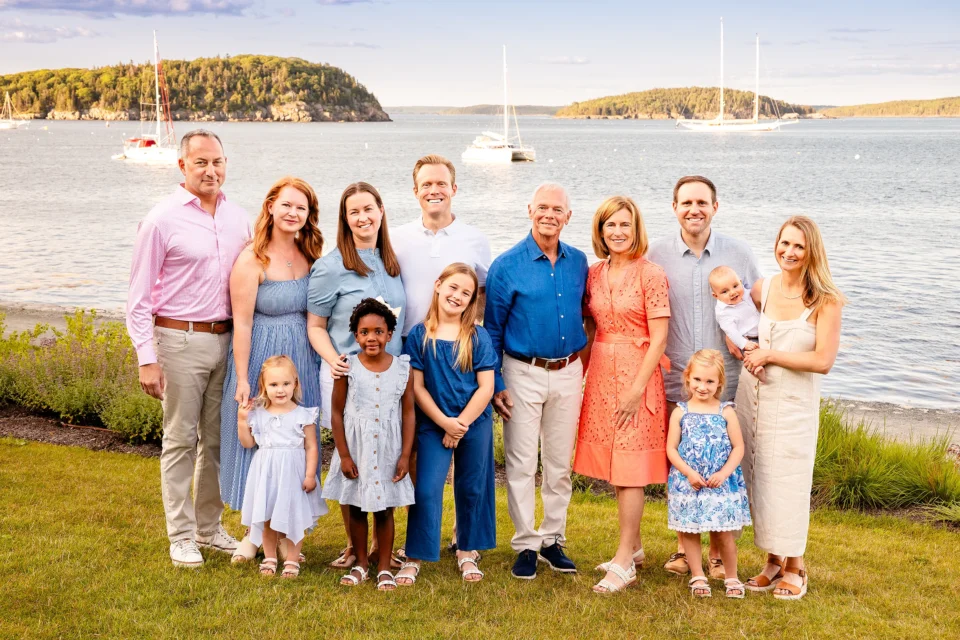 A family smiles and poses for an extended portrait session in front of Frenchman Bay at the Bar Harbor Inn & Spa in Bar Harbor, Maine.