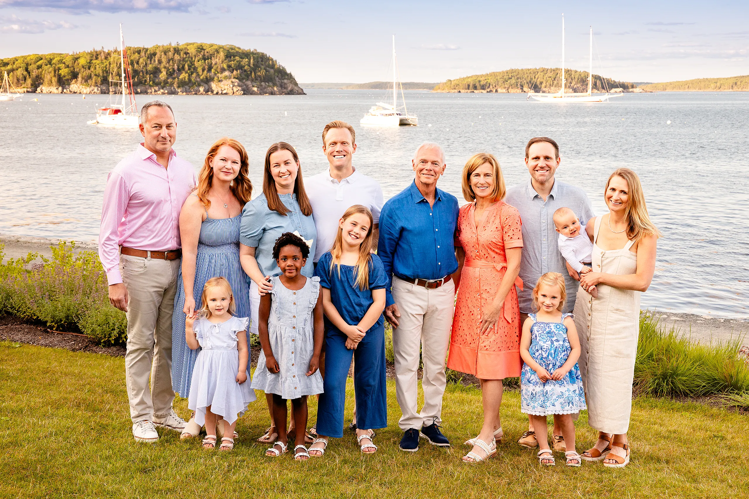 A family smiles and poses for an extended portrait session in front of Frenchman Bay at the Bar Harbor Inn & Spa in Bar Harbor, Maine.