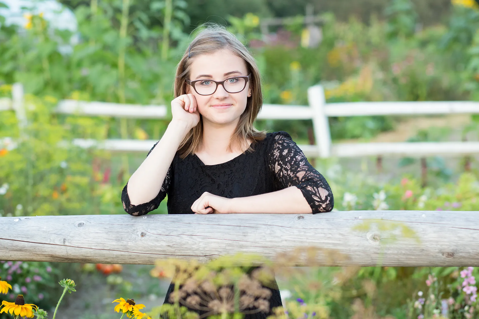maine portrait photography emma 15 A girl smiles and posing in a garden during a senior portrait session at Rogers Farmer near the University of Maine in Orono.