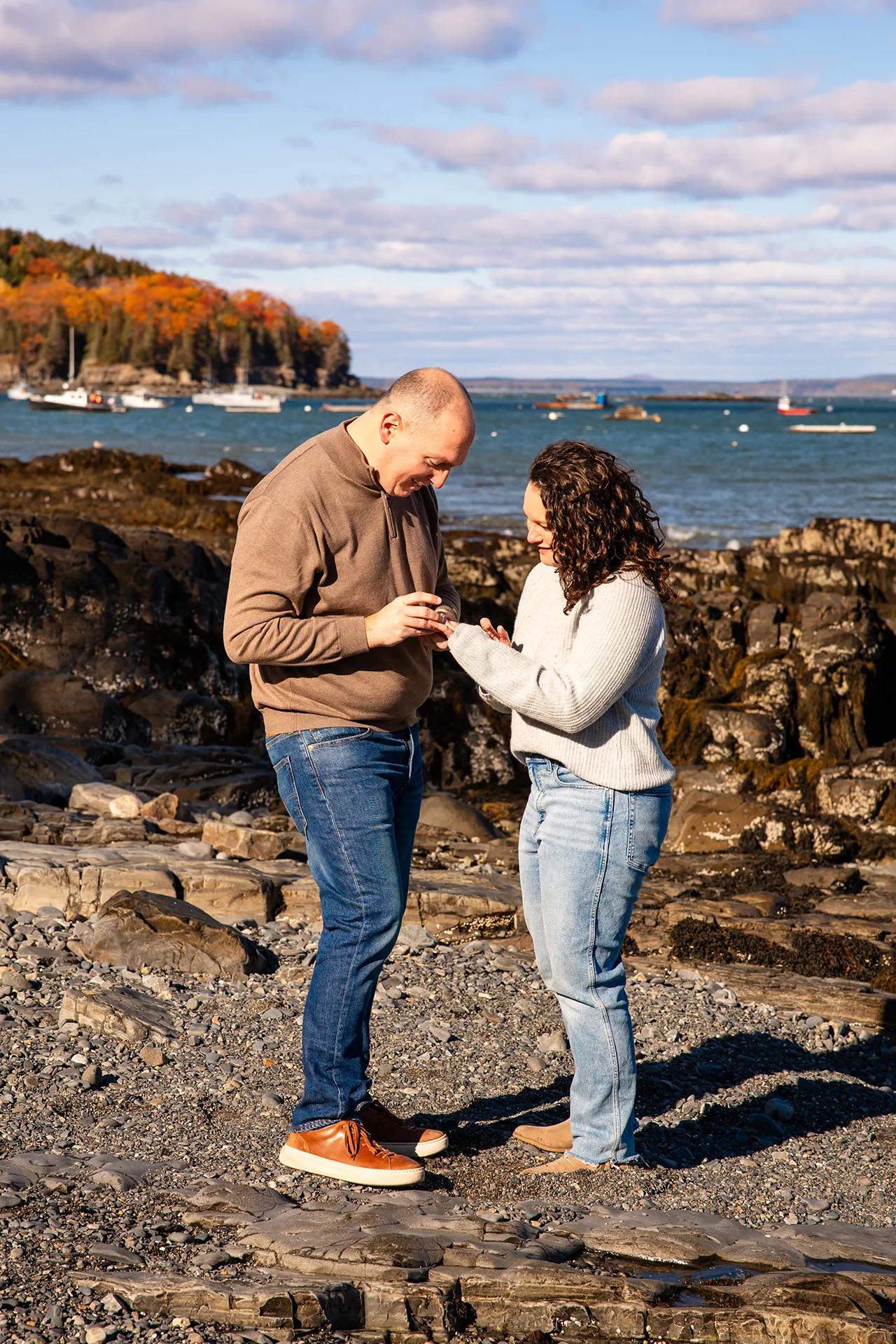 A man slides a ring on a woman's figure during a marriage proposal at the Bar Harbor Inn and Spa near Acadia National Park.