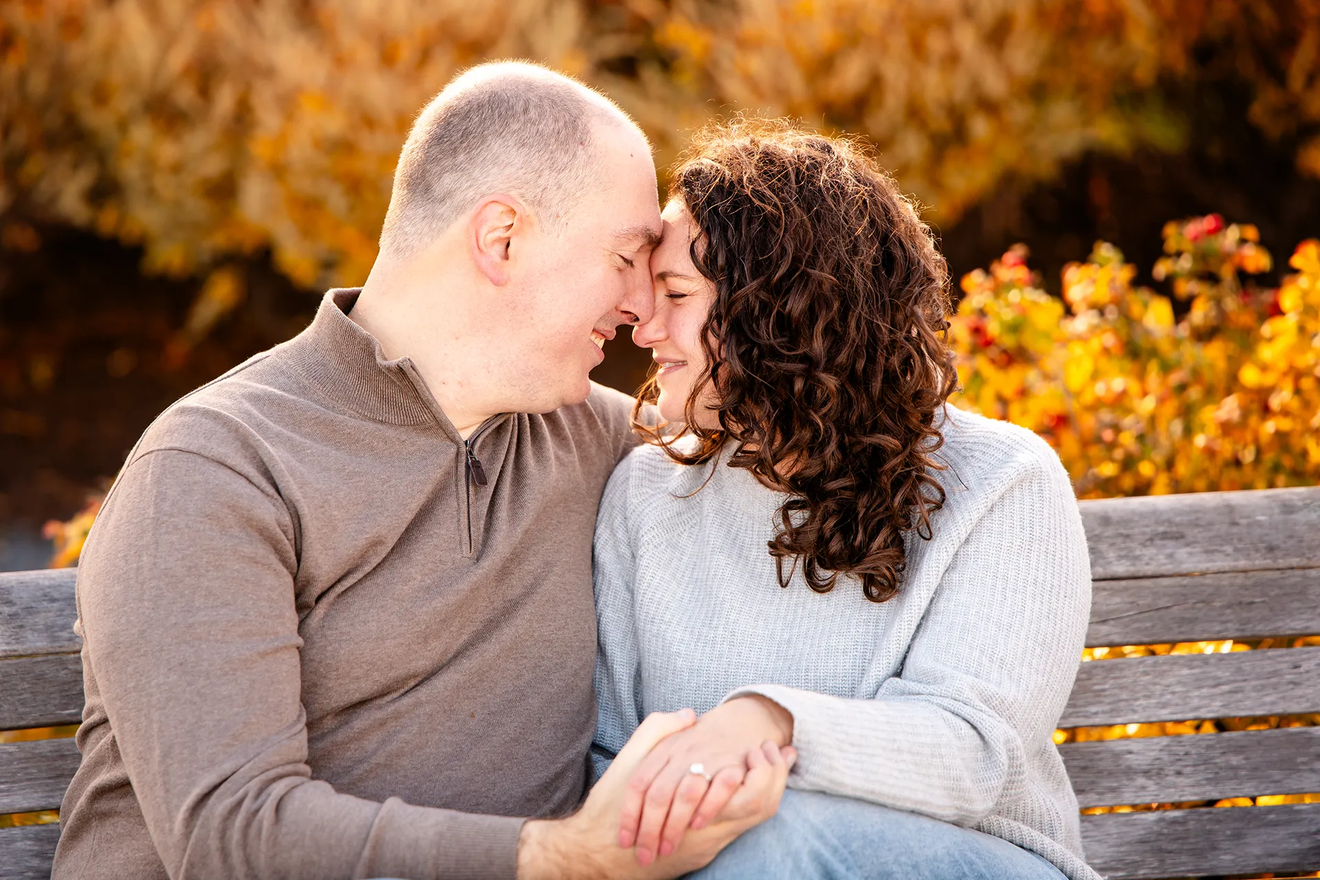 A man and woman rest their heads together during engagement portraits at the Bar Harbor Inn and Spa near Acadia National Park.