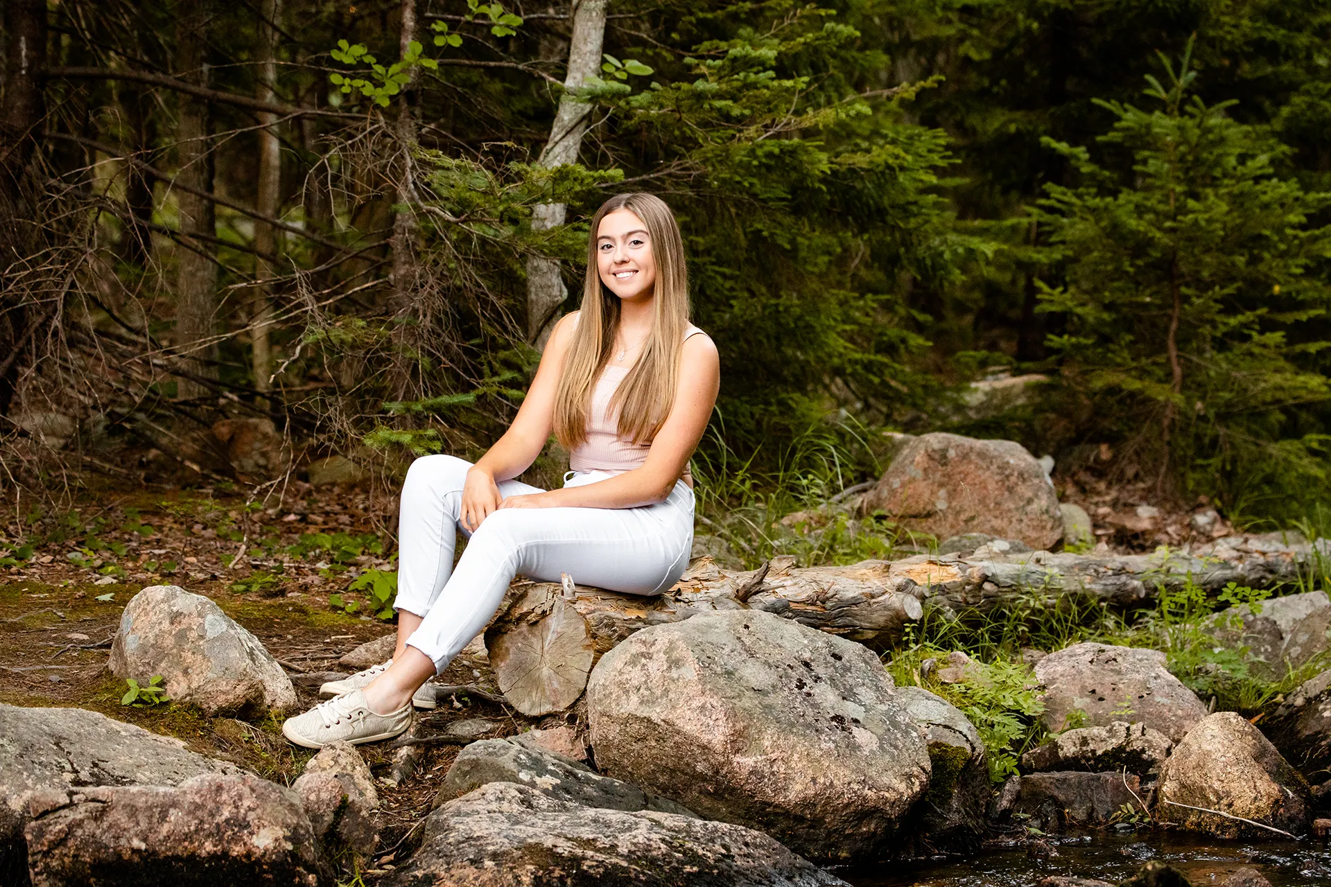 maine senior photography brooke 05 A high school senior smiles and sits on a rock during a portrait session at Jordan Pond in Acadia National Park, Maine.