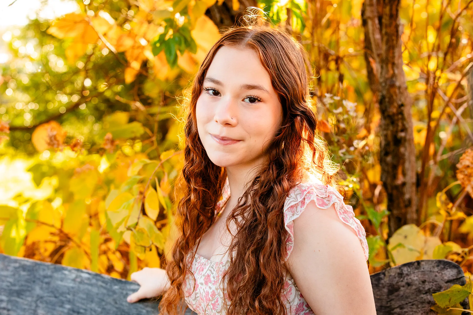 A high school senior sits on a bench during a portrait session at the LIttlefield Ornamentals Garden at the University of Maine.