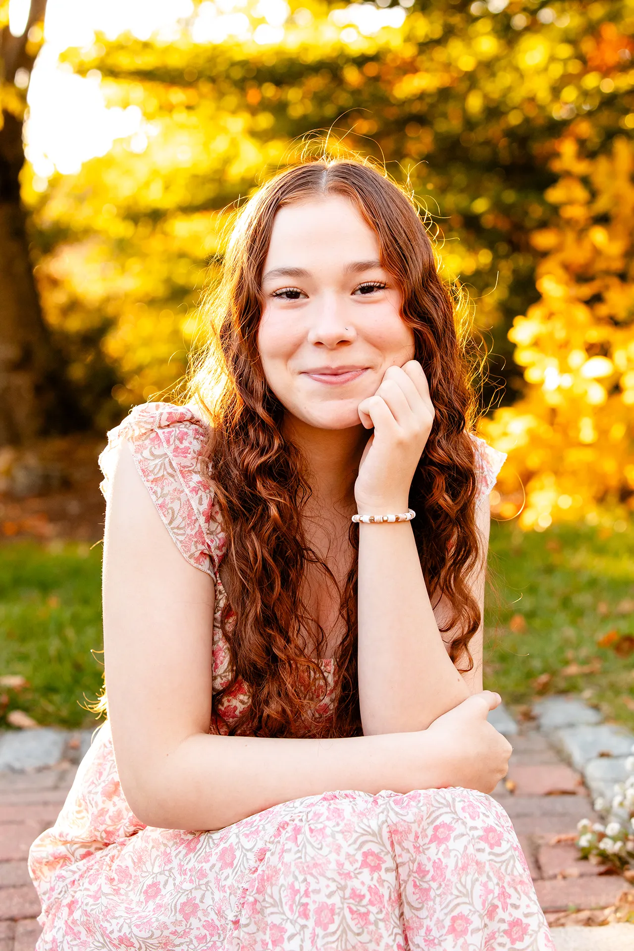 A high school senior sits and poses during a portrait session at the LIttlefield Ornamentals Garden at the University of Maine.