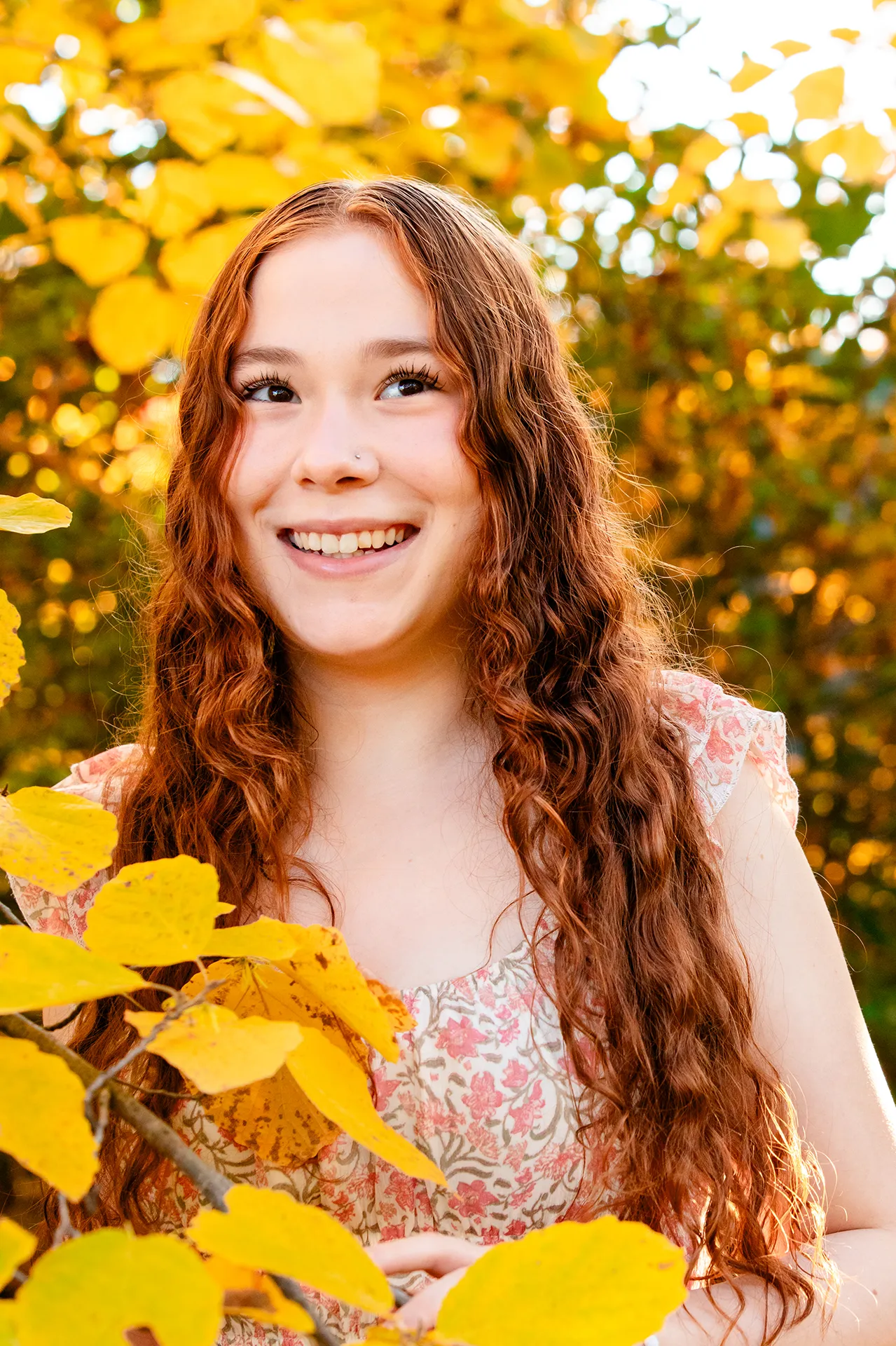 A high school senior laughs during a fall portrait session at the LIttlefield Ornamentals Garden at the University of Maine.