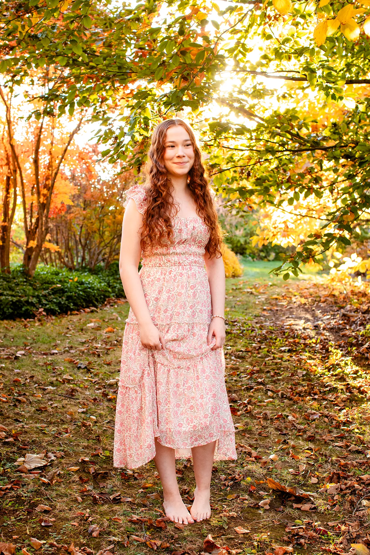 A girl poses amongst some trees during a senior portrait session at the LIttlefield Ornamentals Garden at the University of Maine.