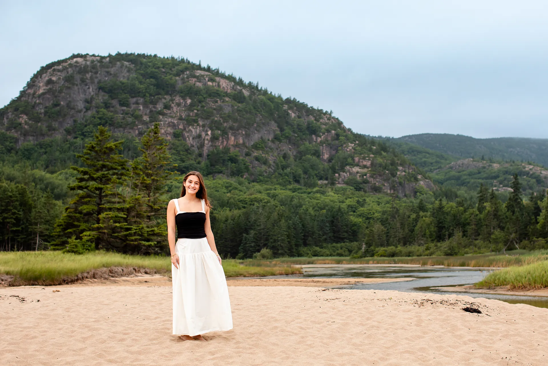 A high school senior poses in front of Beehive Mountain during a senior portrait session in Acadia National Park.