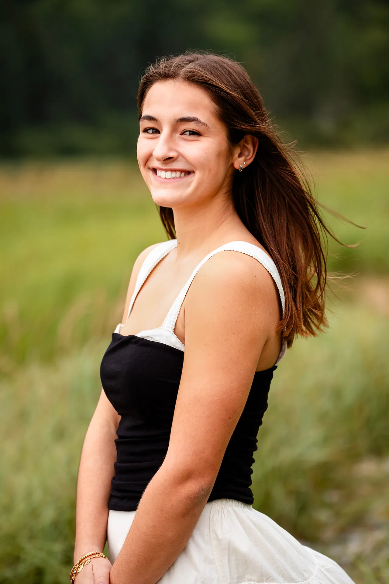 A girl smiles and poses during a high school senior portrait session at Sand Beach in Acadia National Park.