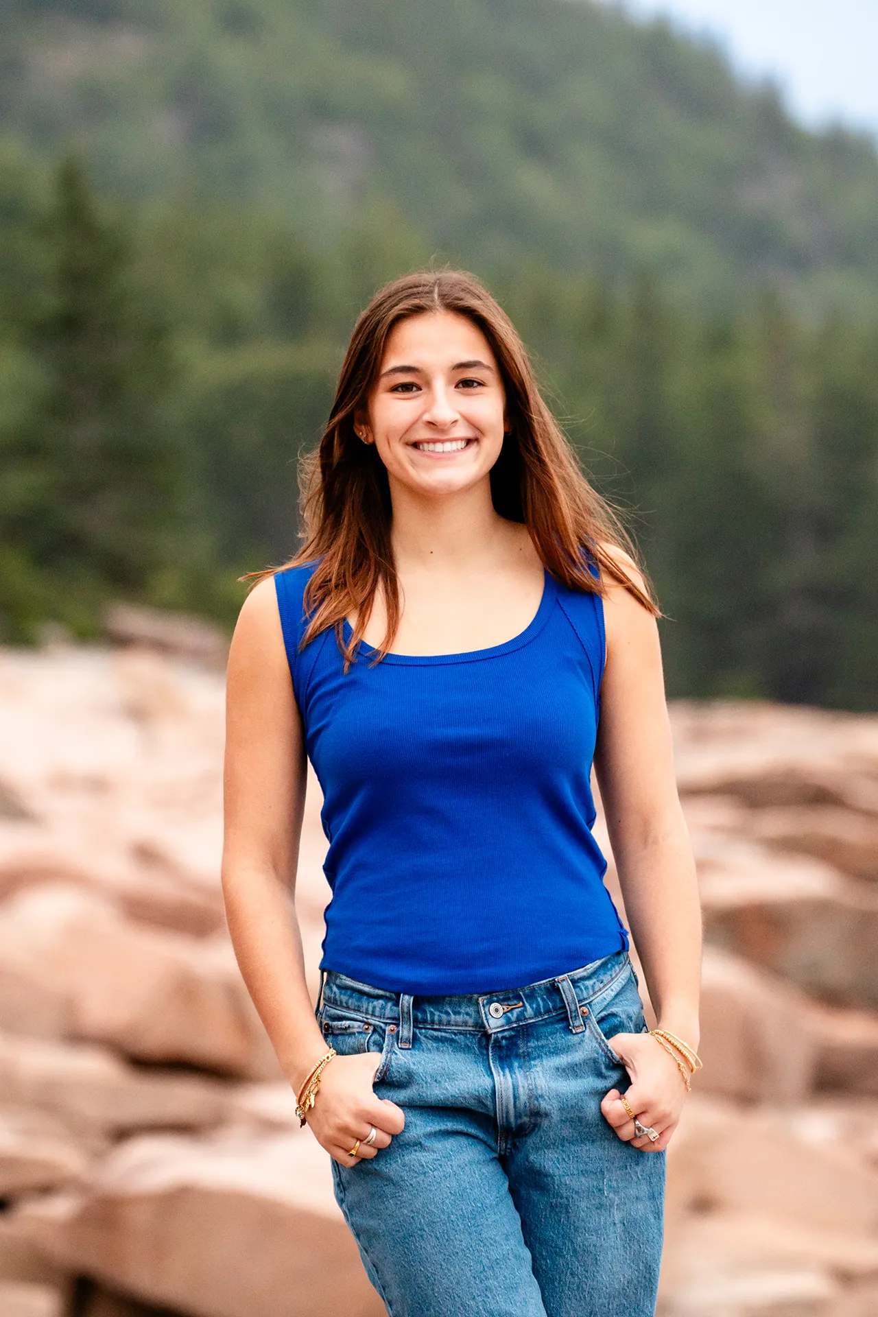 A girl smiles and poses during a high school senior portrait session near the Otter Cliff in Acadia National Park, Maine.