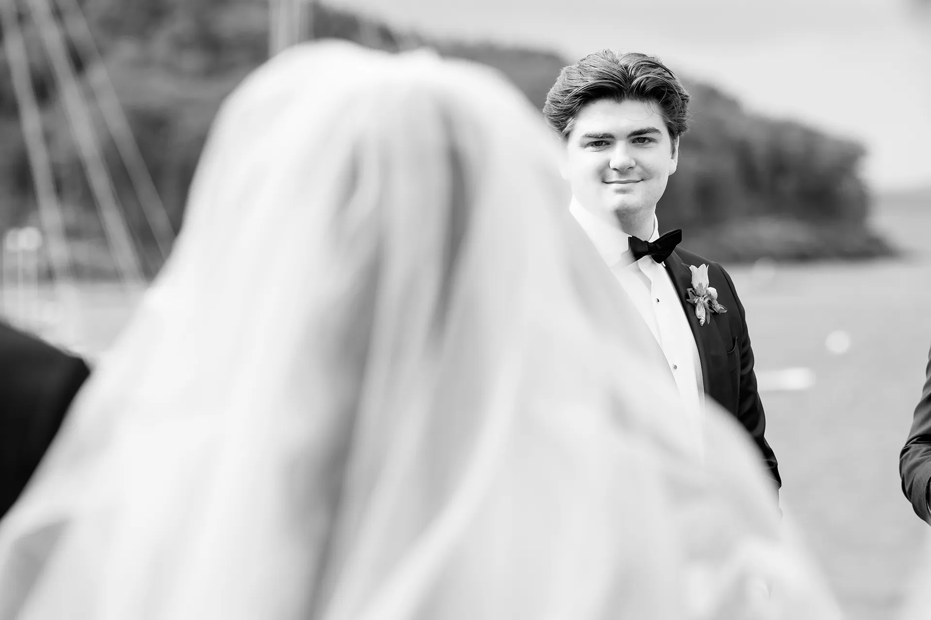 A groom smiles at a bride as she walks down the aisle during a wedding ceremony at the Bar Harbor Inn and Spa in Maine.