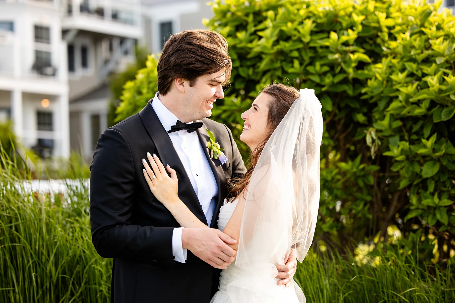A bride and groom smile at each other during wedding portraits at the Bar Harbor Inn and Spa near Acadia National Park in Maine.