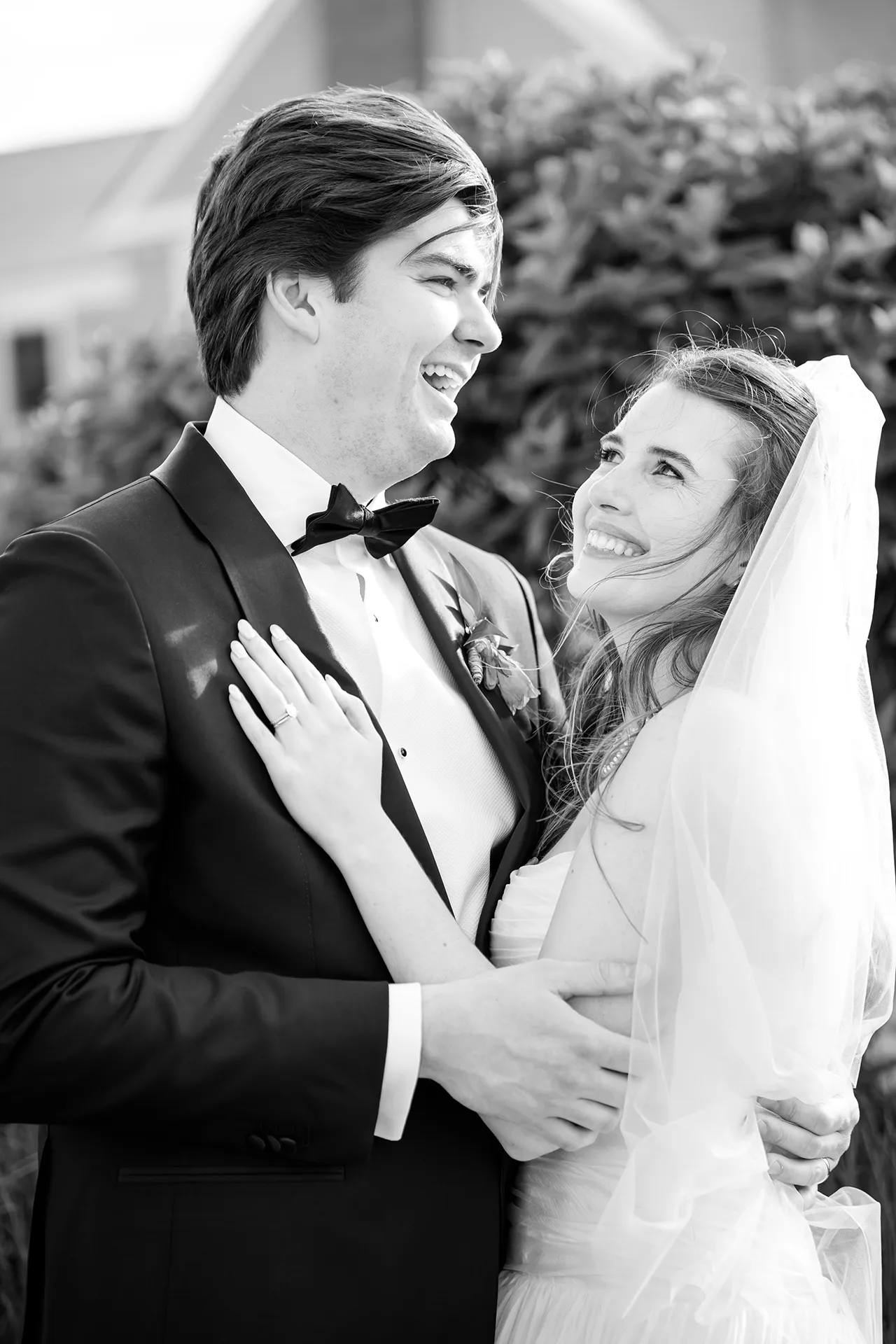 A bride smiles at a groom while he laughs other during wedding portraits at the Bar Harbor Inn and Spa near Acadia National Park in Maine.