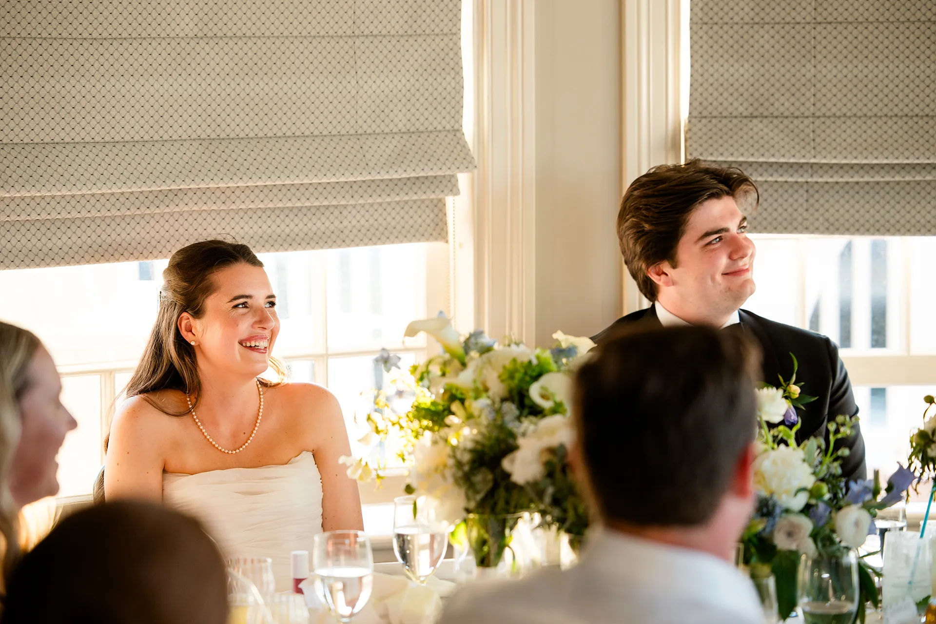 A bride and groom smile as they listen to a toast during a wedding reception in the Porcupine Room at the Bar Harbor Inn and Spa in Maine.