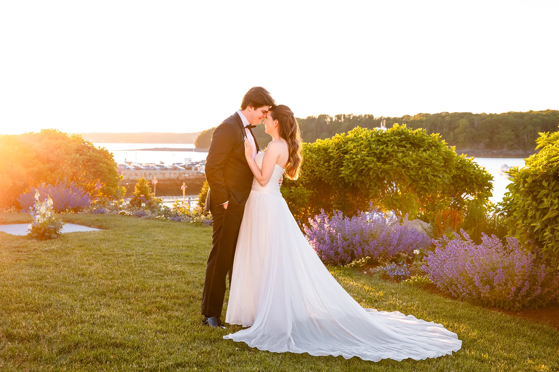 A bride and groom rest their foreheads together as the sunsets during their wedding portraits at the Bar Harbor Inn and Spa in Maine.