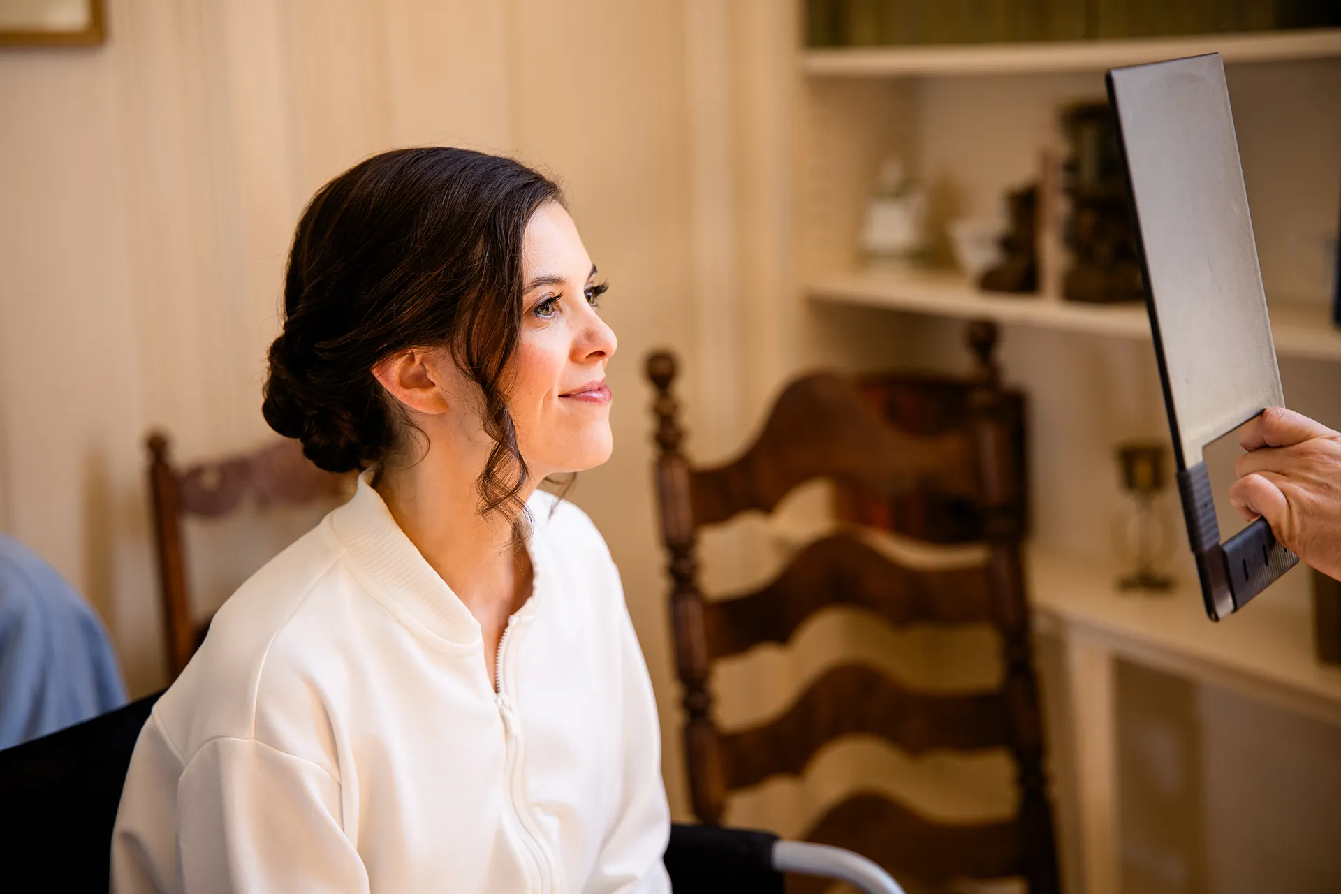 A bride smiles as she looks at herself in the mirror while getting ready for her wedding at the Atlantic Oceanside and Event Center in Bar Harbor, Maine.