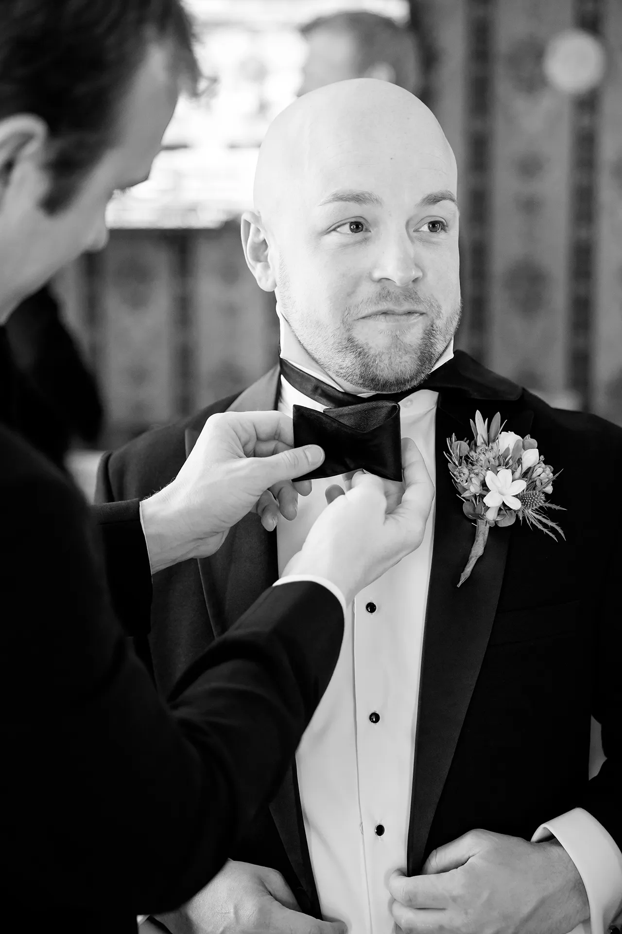 A groomsman helps a groom with his bowtie as he getting ready for his wedding at the Atlantic Oceanside and Event Center in Bar Harbor, Maine.