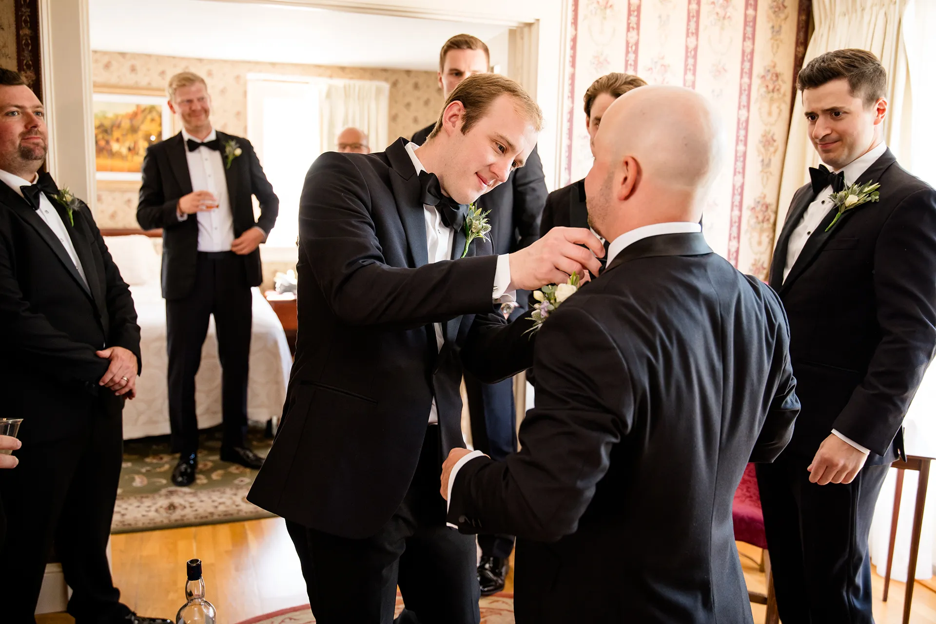 A groomsman helps a groom with his bowtie while other groomsmen watch for at the Atlantic Oceanside and Event Center in Bar Harbor, Maine.