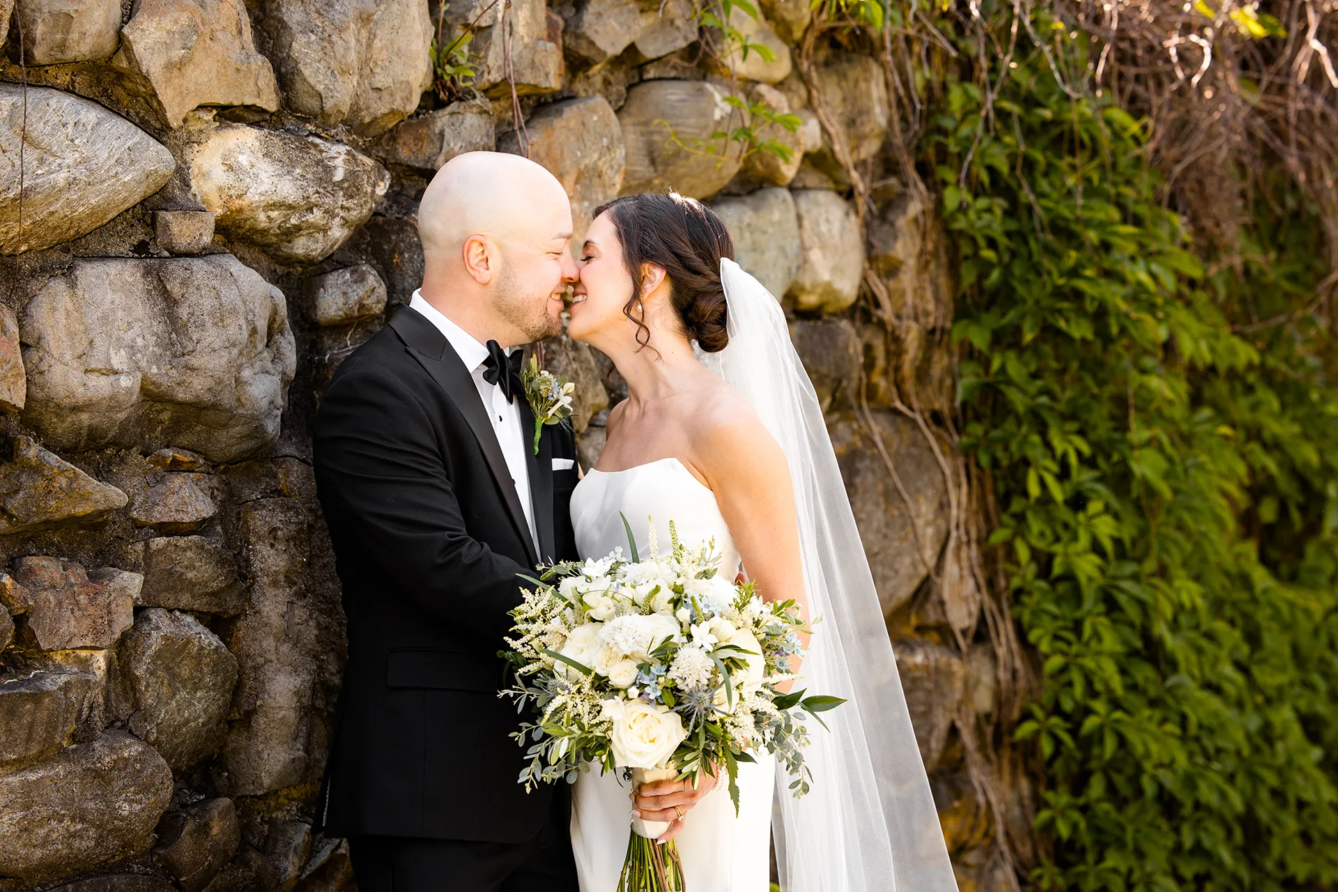 A bride and groom rub noses and smile during wedding portraits at the Atlantic Oceanside Hotel & Event Center in Bar Harbor, Maine.