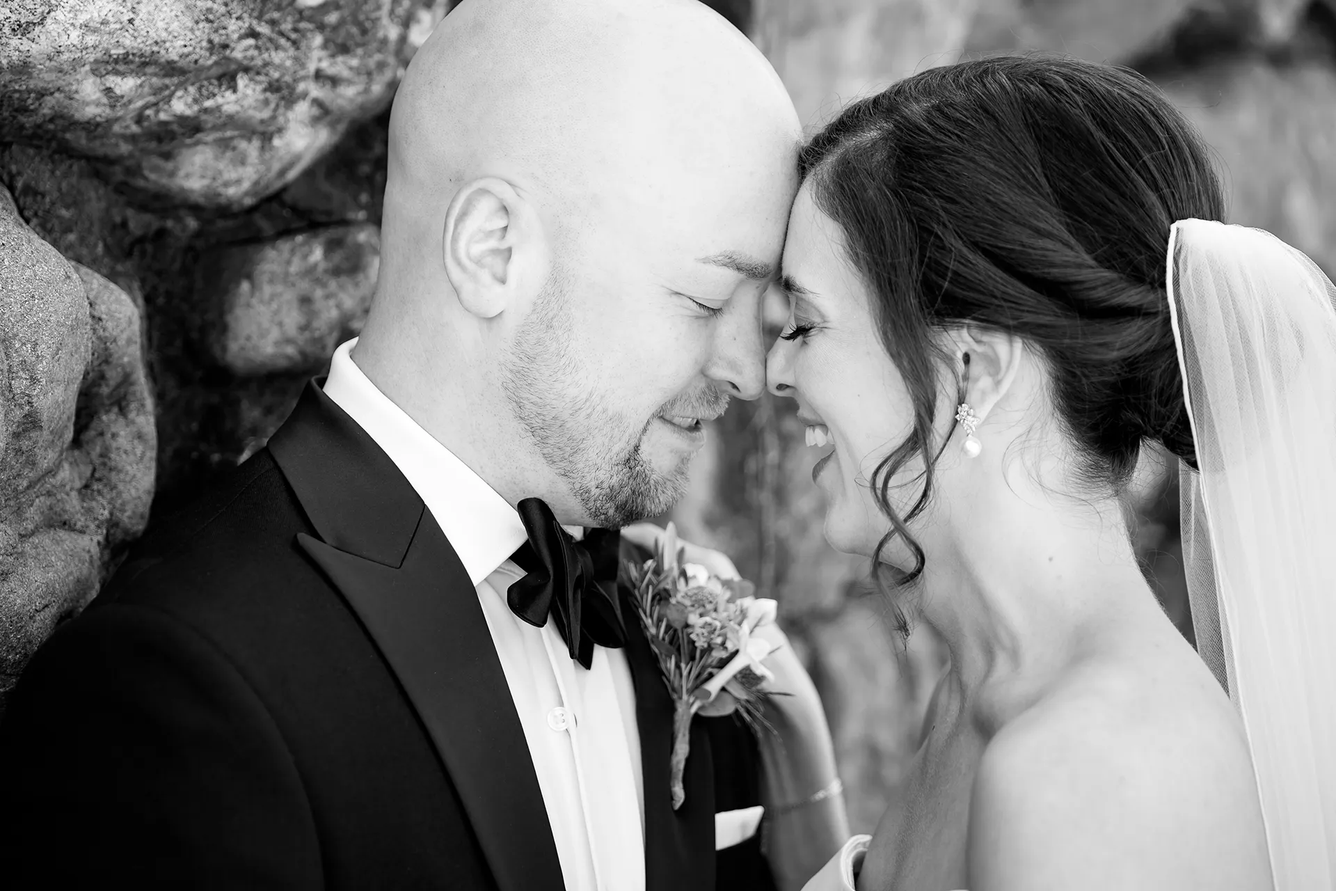 A bride and groom laugh as they rest their foreheads together during wedding portraits at the Atlantic Oceanside Hotel & Event Center in Bar Harbor, Maine.