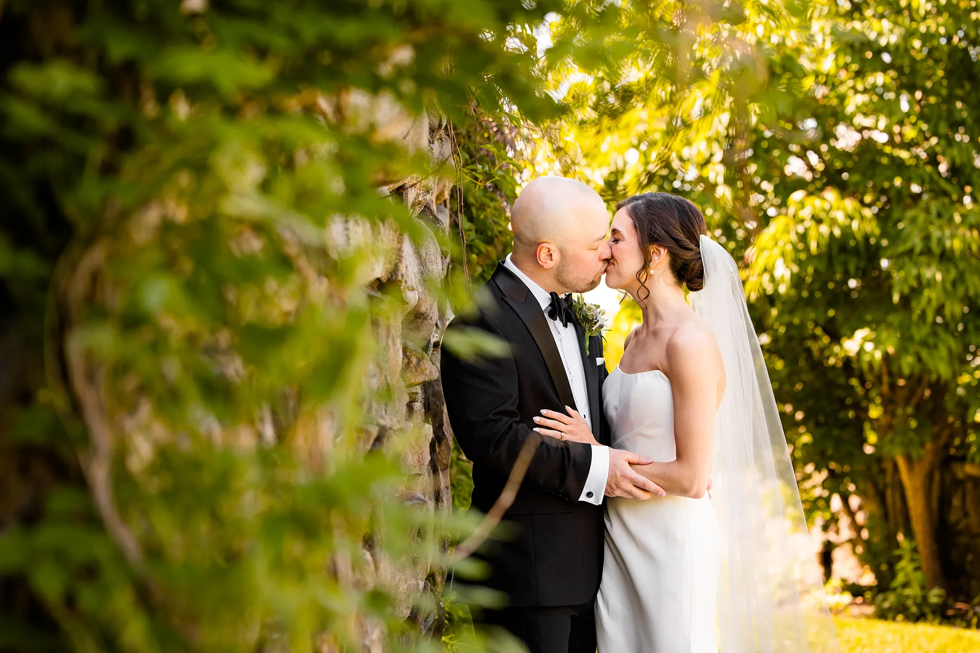 A newly married couple kiss in a garden during wedding portraits at the Atlantic Oceanside Hotel & Event Center in Bar Harbor, Maine.