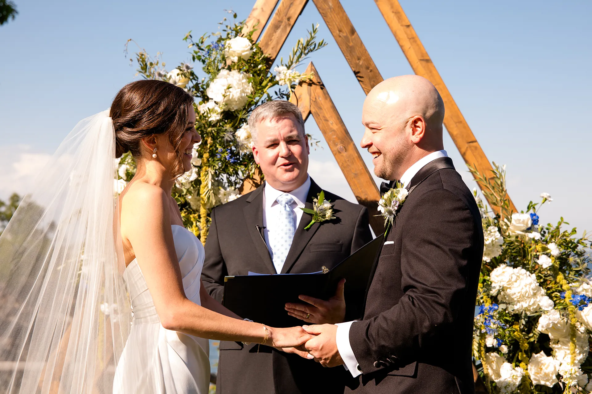 A bride and groom hold hands and smile at each other during a wedding ceremony at the Atlantic Oceanside Hotel & Event Center in Bar Harbor, Maine.