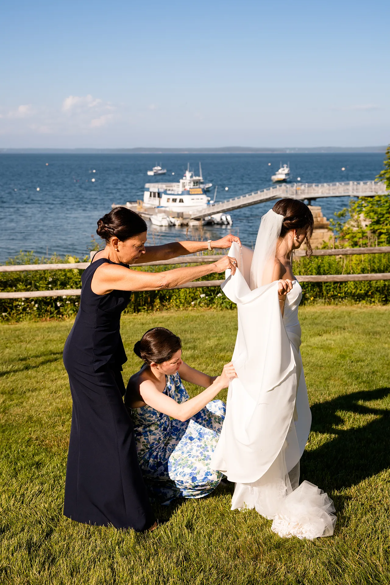 A bridesmaid and mom help a bride bustle her dress during a wedding at the Atlantic Oceanside Hotel & Event Center in Bar Harbor, Maine.