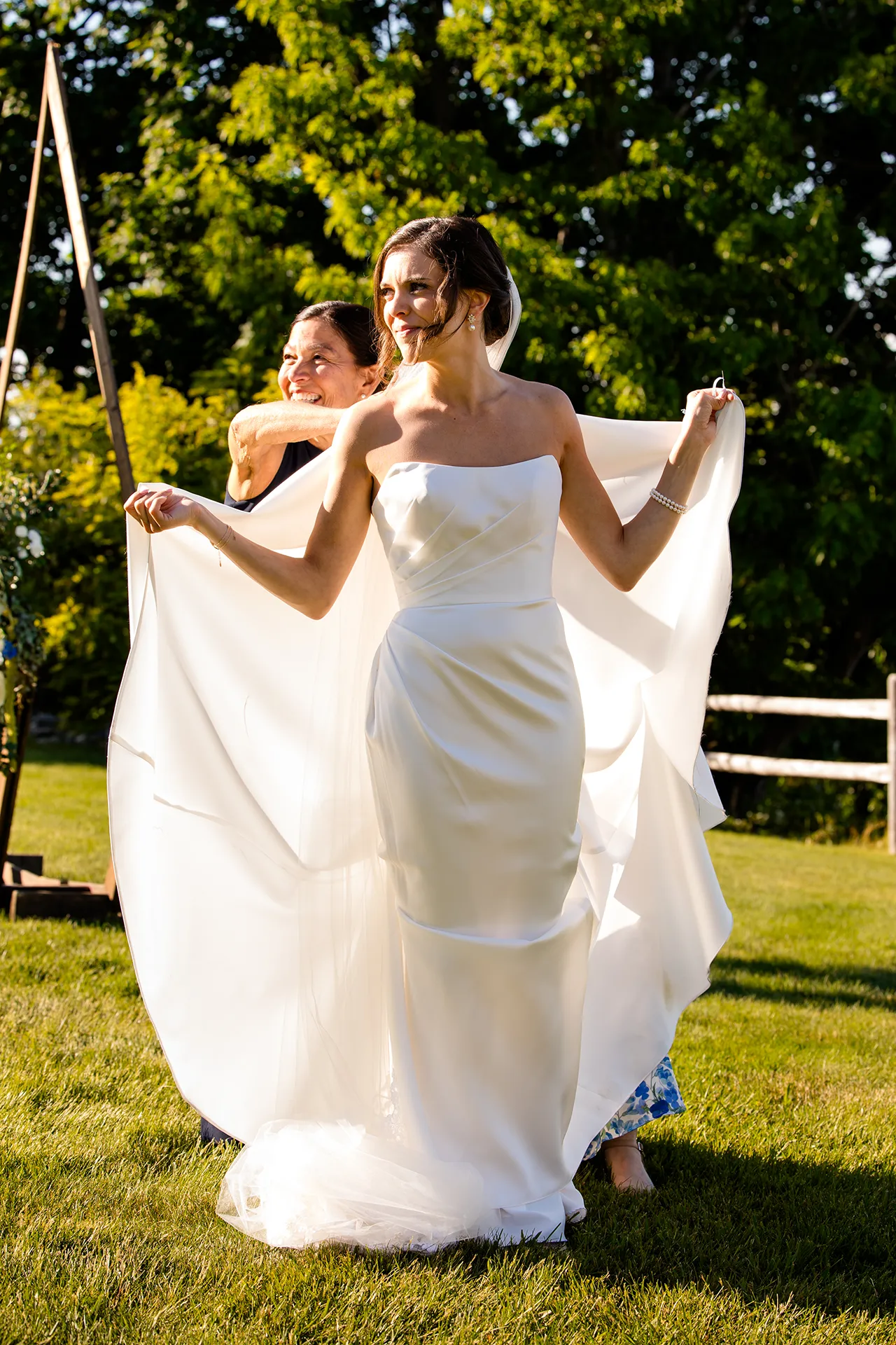 A bride holds up her dress as her mom helps her bustle it during a wedding at the Atlantic Oceanside Hotel & Event Center in Bar Harbor, Maine.