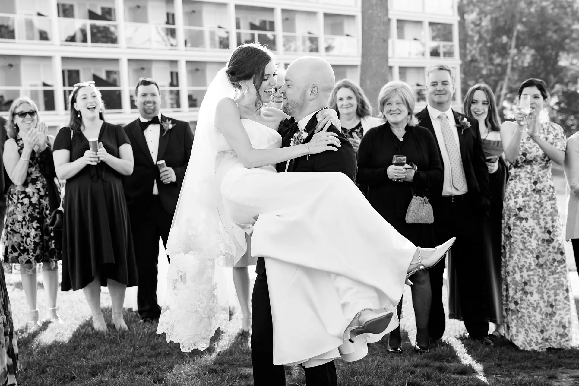 A groom picks up a bride as guests smile during a first dance outside at the Atlantic Oceanside Hotel & Event Center in Bar Harbor, Maine.