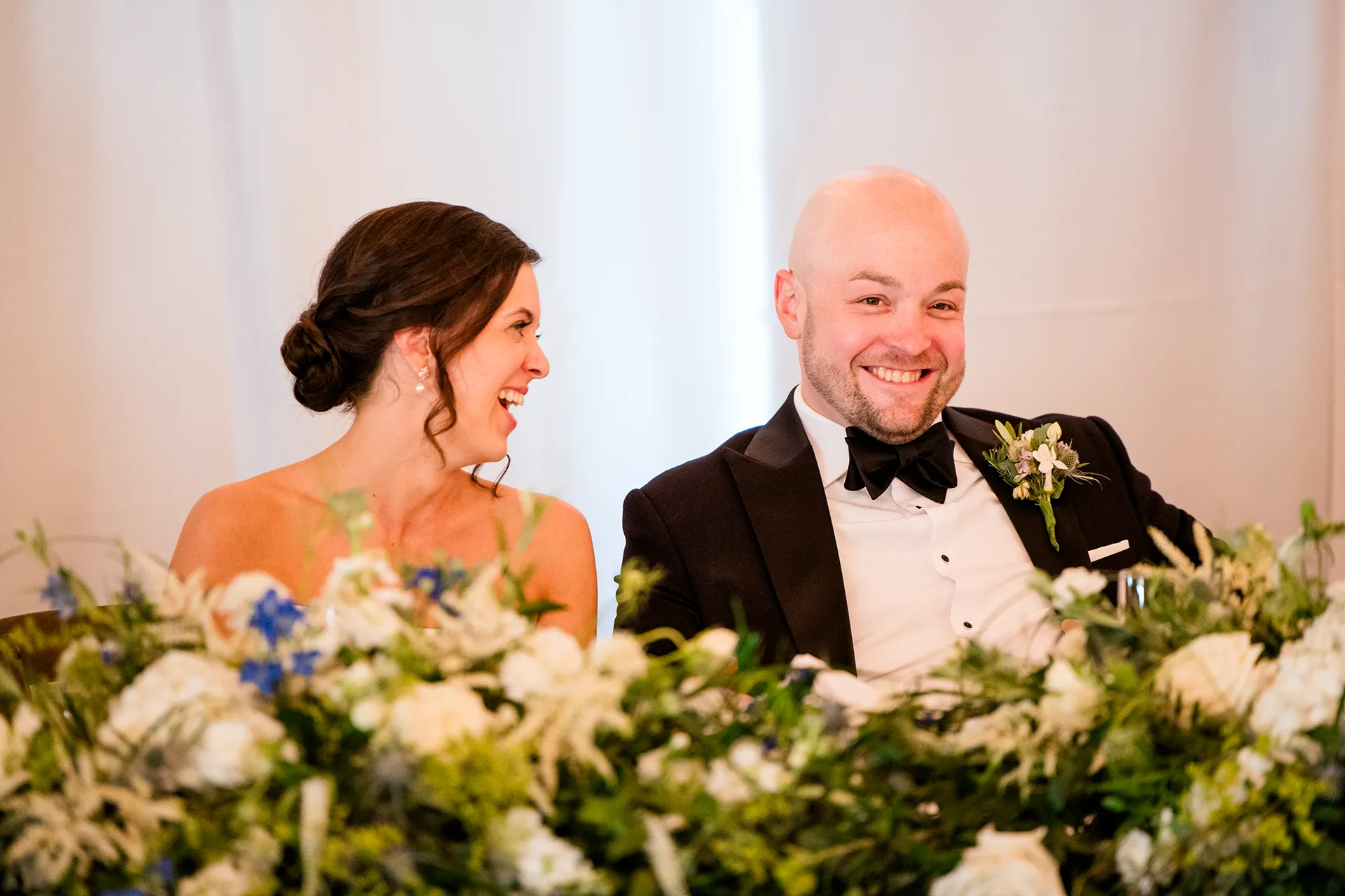 Bride and groom laugh as they listen to a toast during a wedding reception at the Atlantic Oceanside Hotel & Event Center in Bar Harbor, Maine.