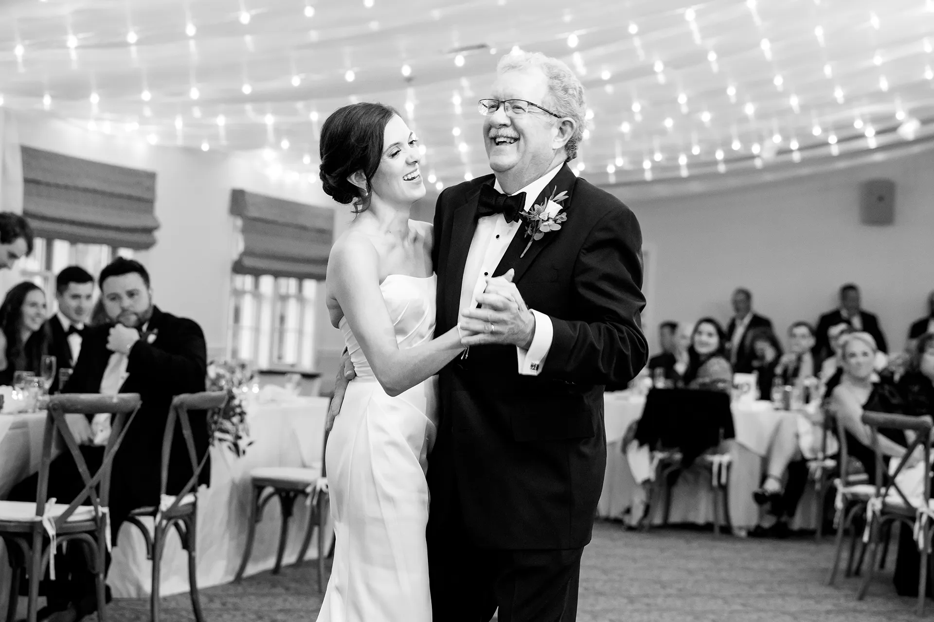 A dad and bride laugh as they share a dance during a wedding reception at the Atlantic Oceanside Hotel & Event Center in Bar Harbor, Maine.