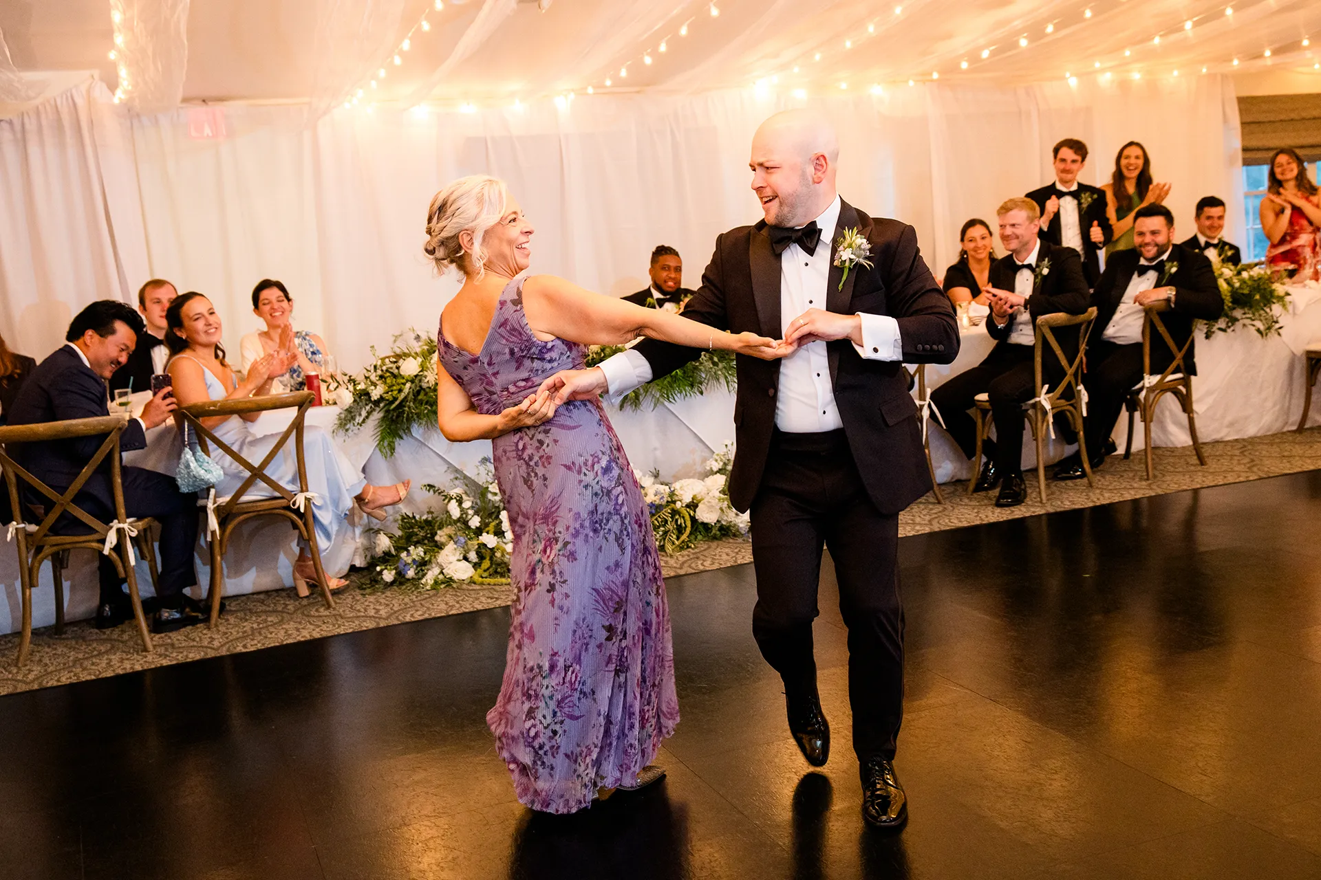 A mom and groom laugh as they share a dance during a wedding reception at the Atlantic Oceanside Hotel & Event Center in Bar Harbor, Maine.