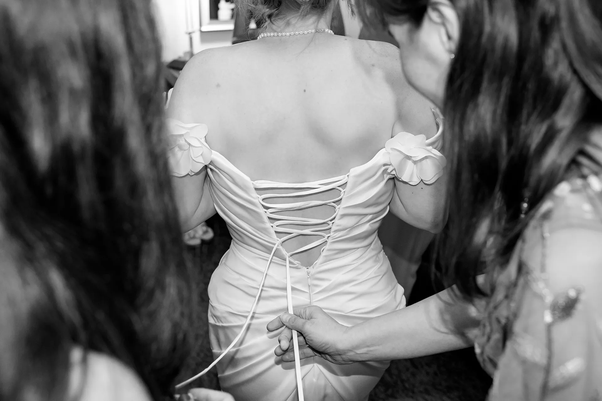 A closeup of a bride getting laced into her wedding dress as she gets ready for a wedding at the Hilton Garden Inn in Bangor, Maine.