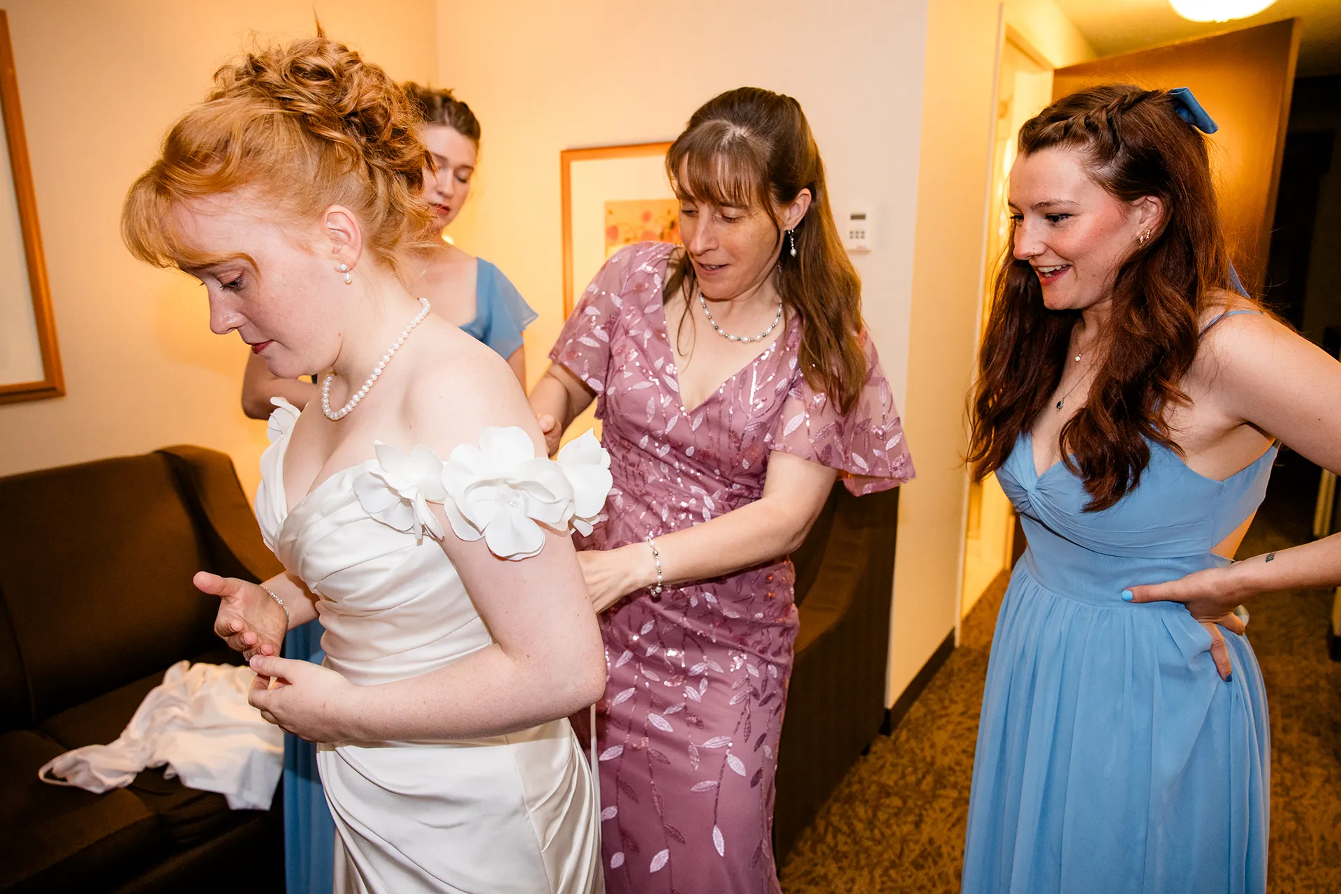 A mom and bridesmaids help a bride info her dress as she gets ready for a wedding at the Hilton Garden Inn in Bangor, Maine.