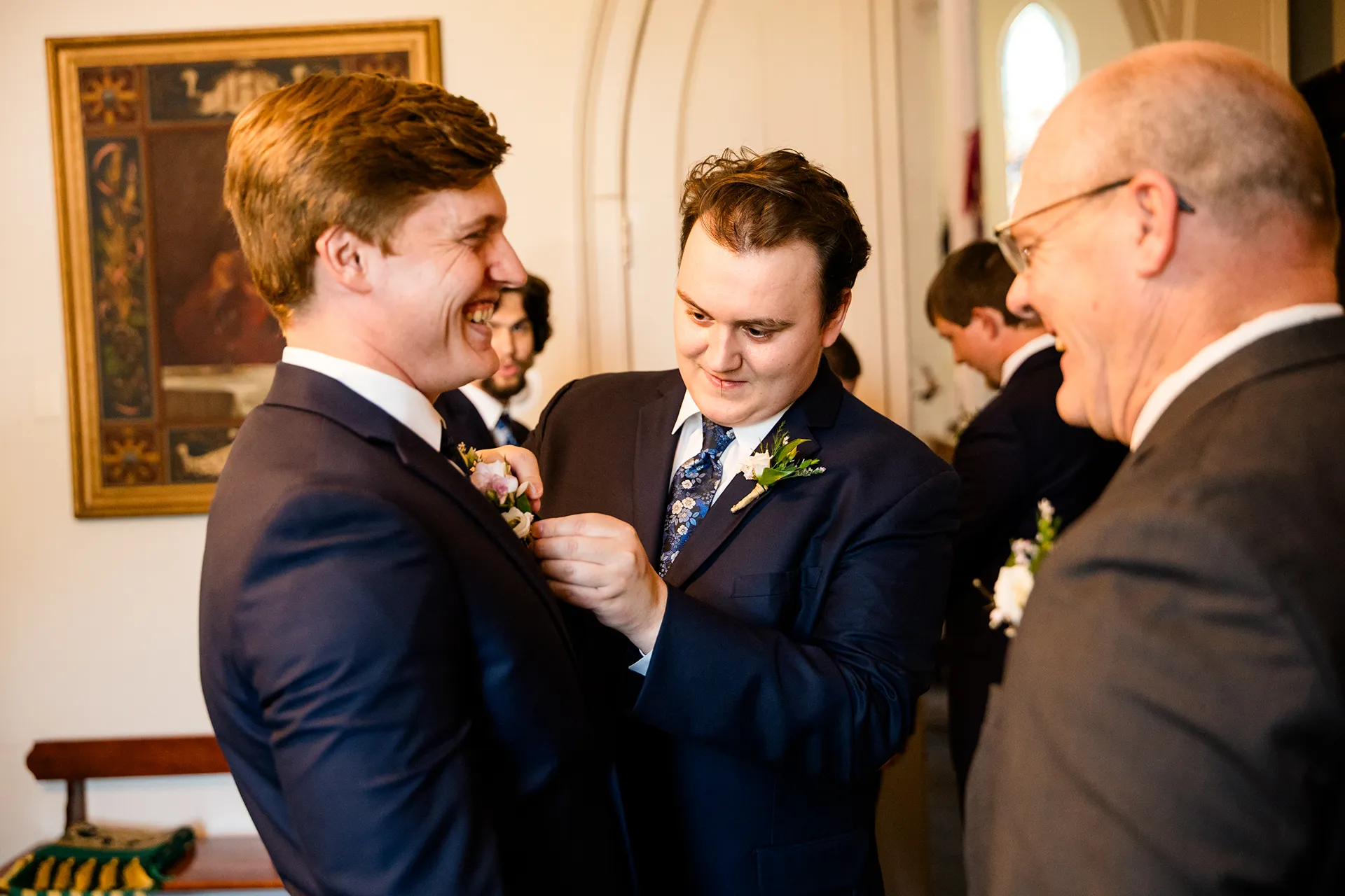 A groomsmen helps a groom put on his boutonniere for a wedding ceremony at Saint John's Catholic Church in Bangor, Maine.