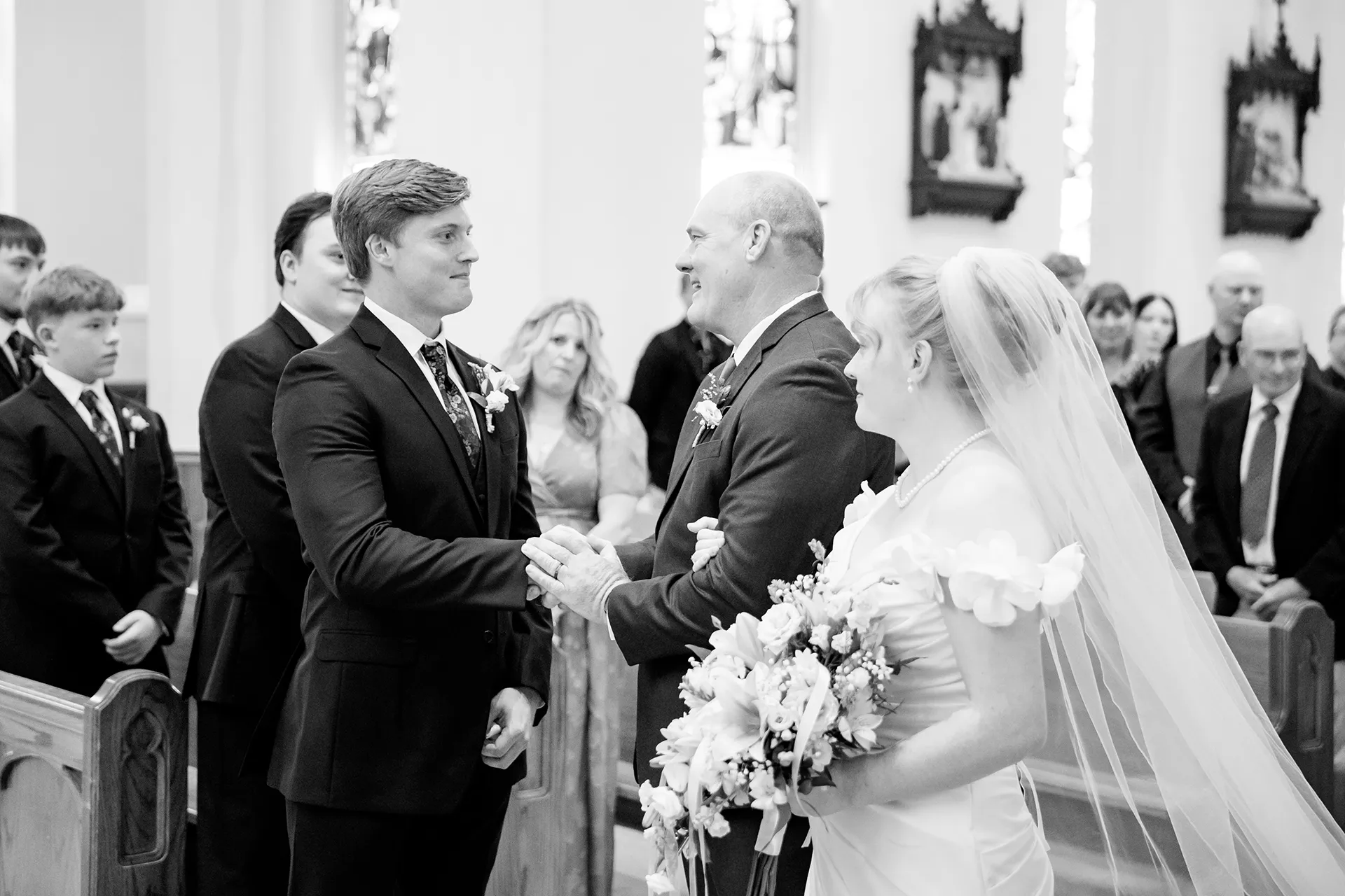 A dad shakes a groom's hand during a wedding ceremony at Saint John's Catholic Church in Bangor, Maine.