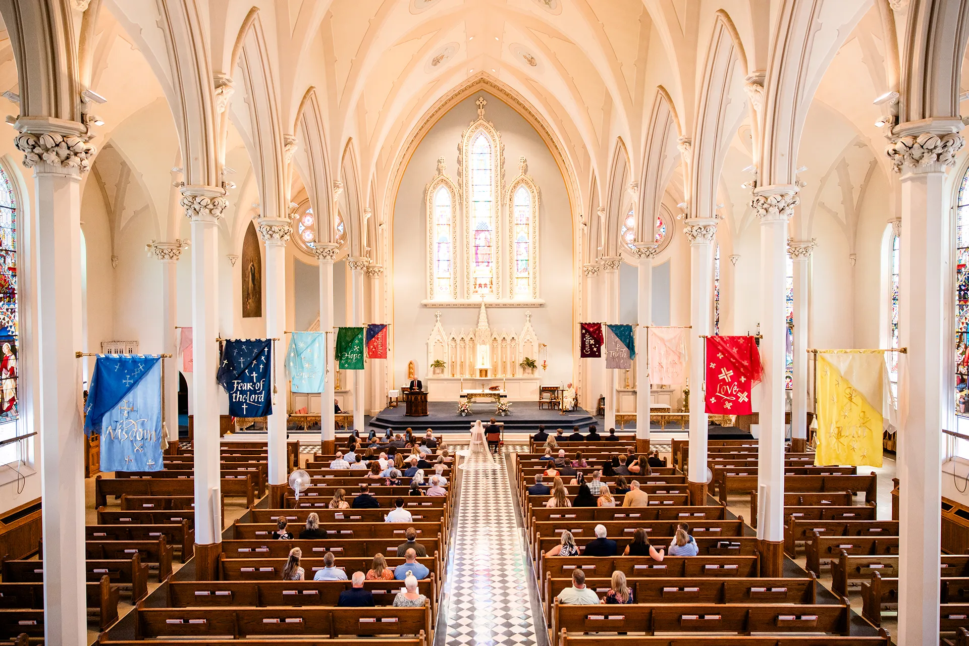 A bride and groom sit at the front of the aisle during a catholic wedding ceremony at Saint John's Catholic Church in Bangor, Maine.