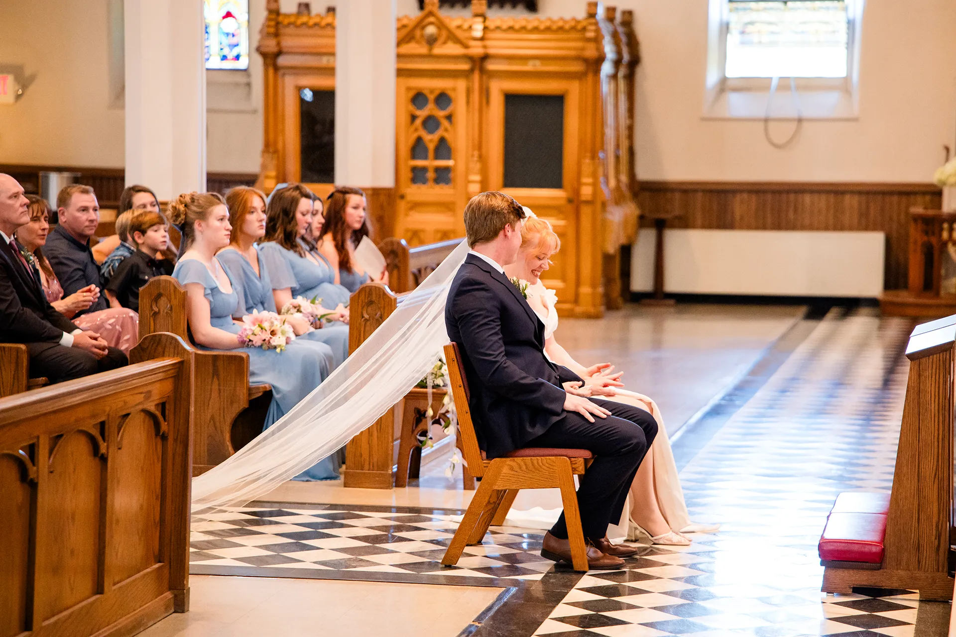 A bride laughs as she holds a groom's hand during a wedding ceremony at Saint John's Catholic Church in Bangor, Maine.
