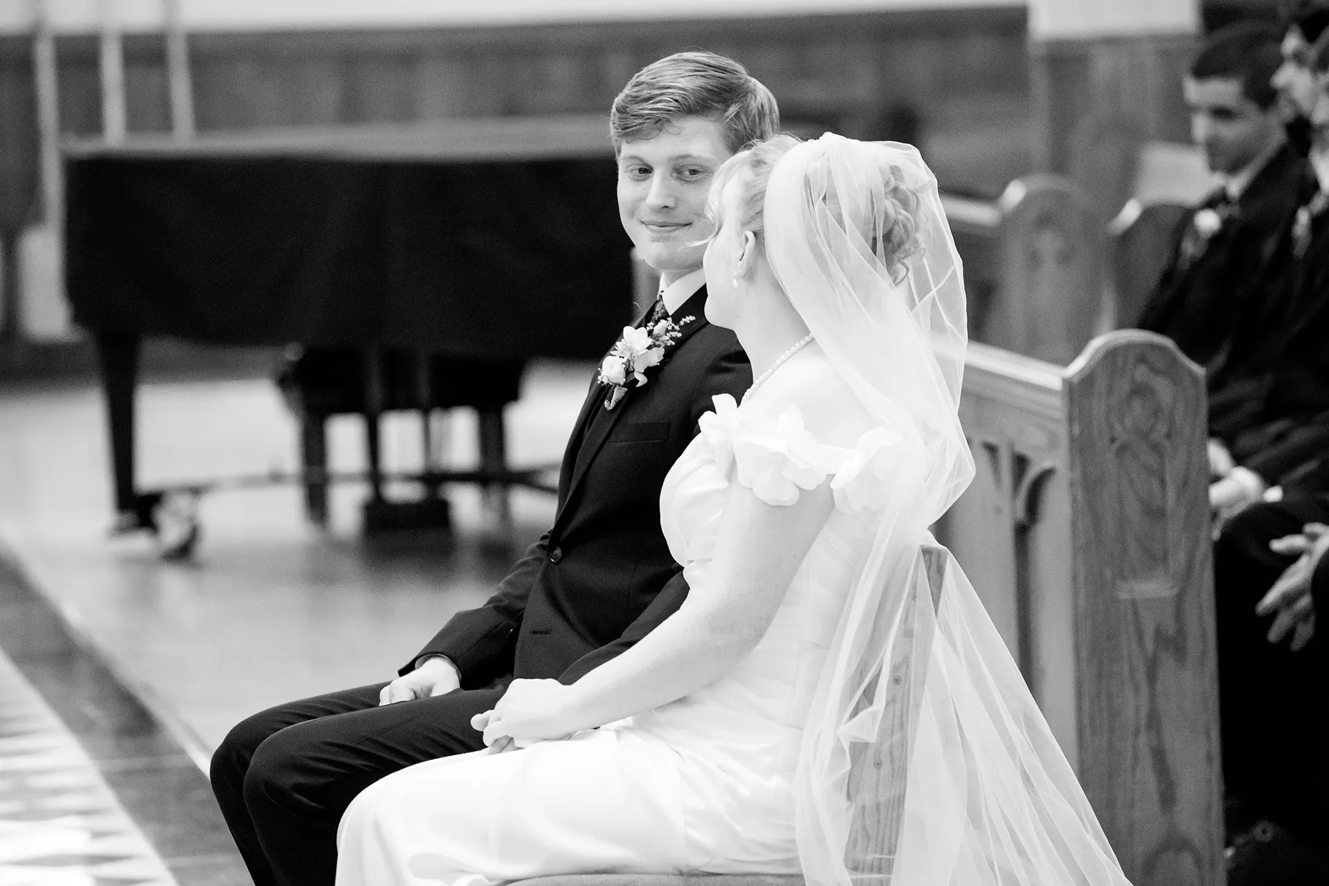 A groom smiles at a bride during a wedding ceremony at Saint John's Catholic Church in Bangor, Maine.