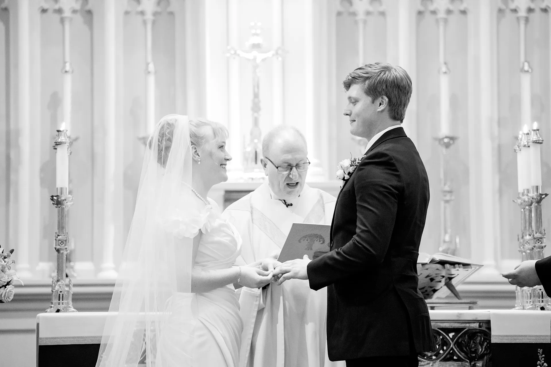A bride smiles as she puts a ring on the groom's hand during a wedding ceremony at Saint John's Catholic Church in Bangor, Maine.