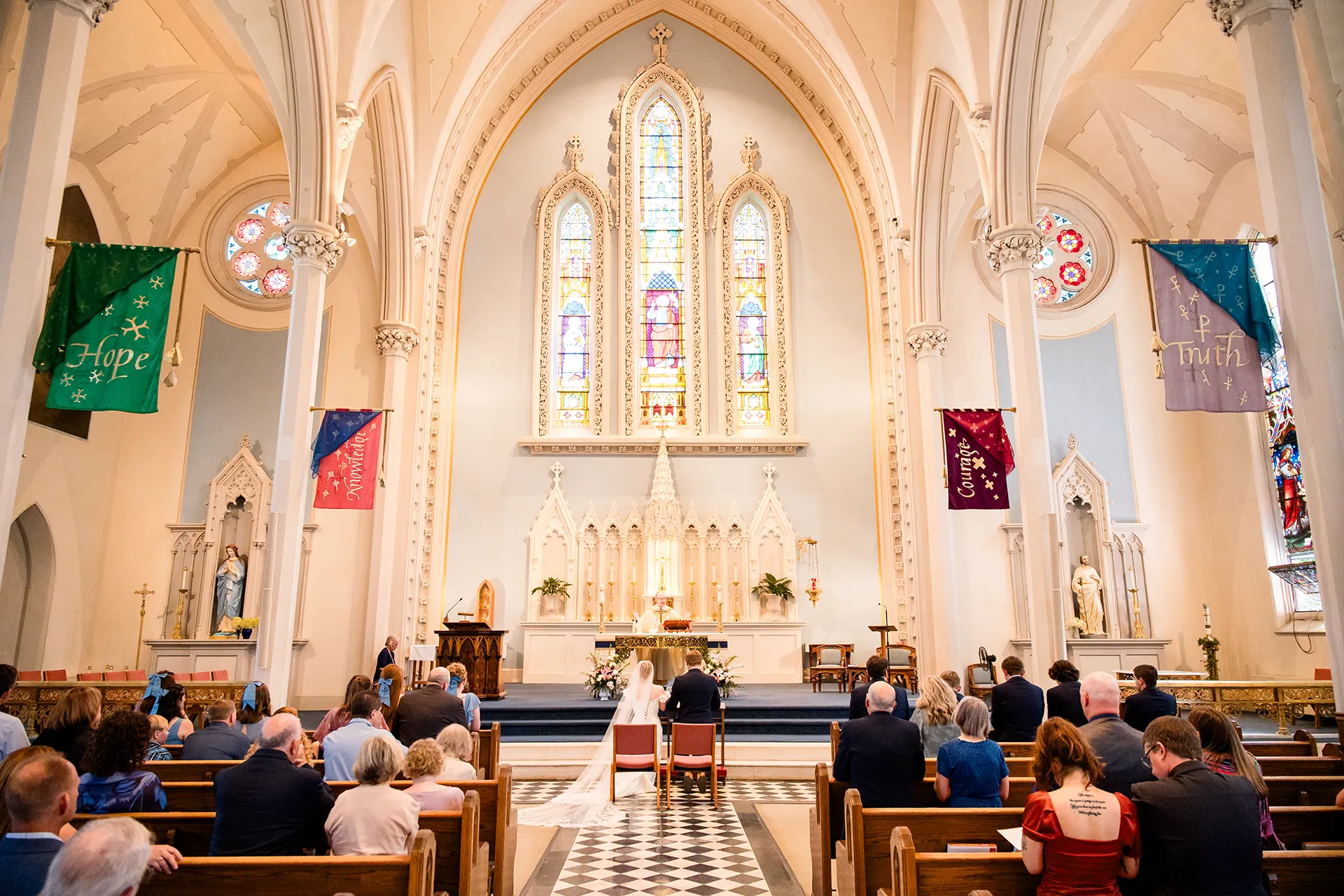 A bride and groom kneel at the head of the aisle during a catholic wedding ceremony at Saint John's Catholic Church in Bangor, Maine.