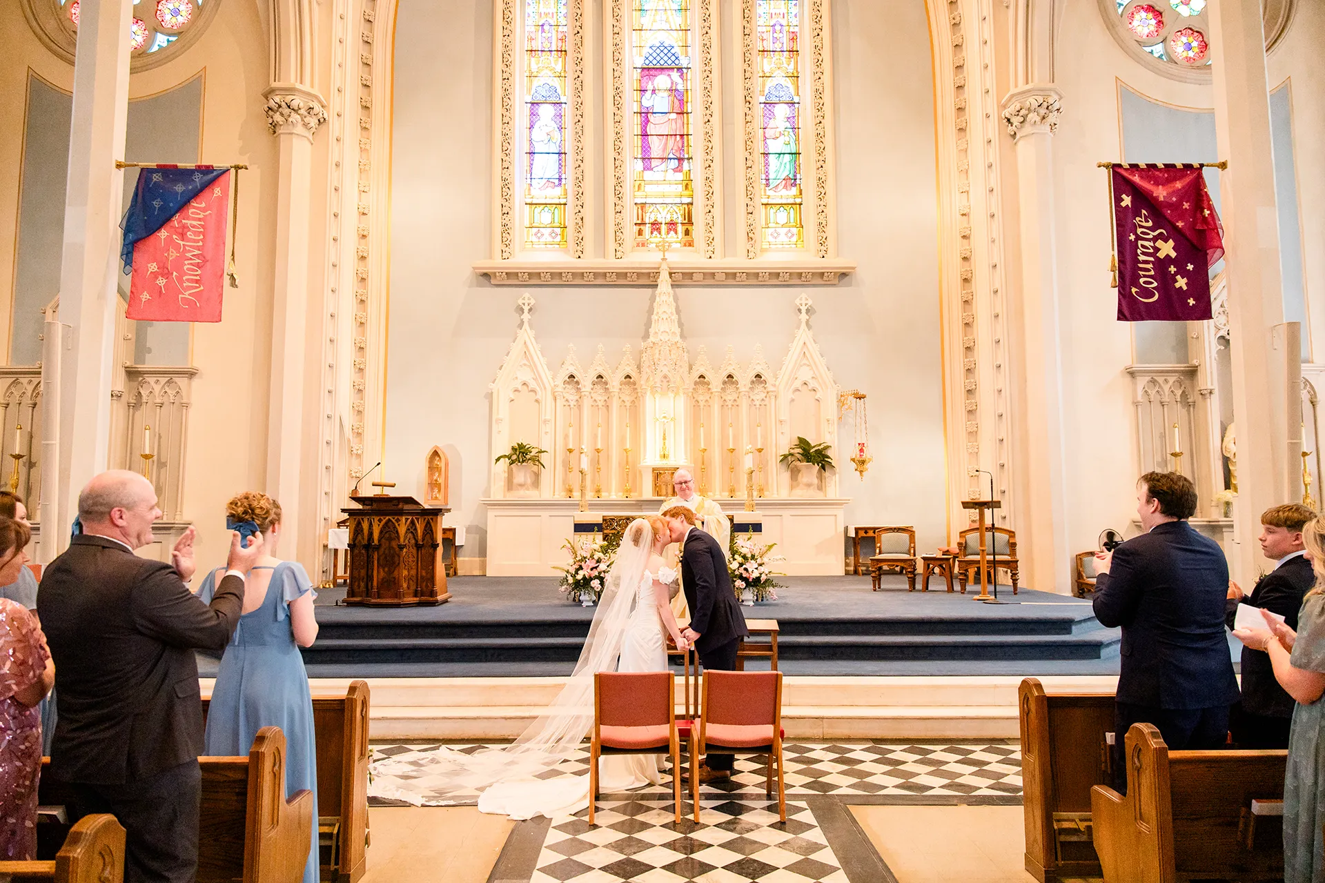 A bride and groom kiss while guests clap during a wedding ceremony at Saint John's Catholic Church in Bangor, Maine.