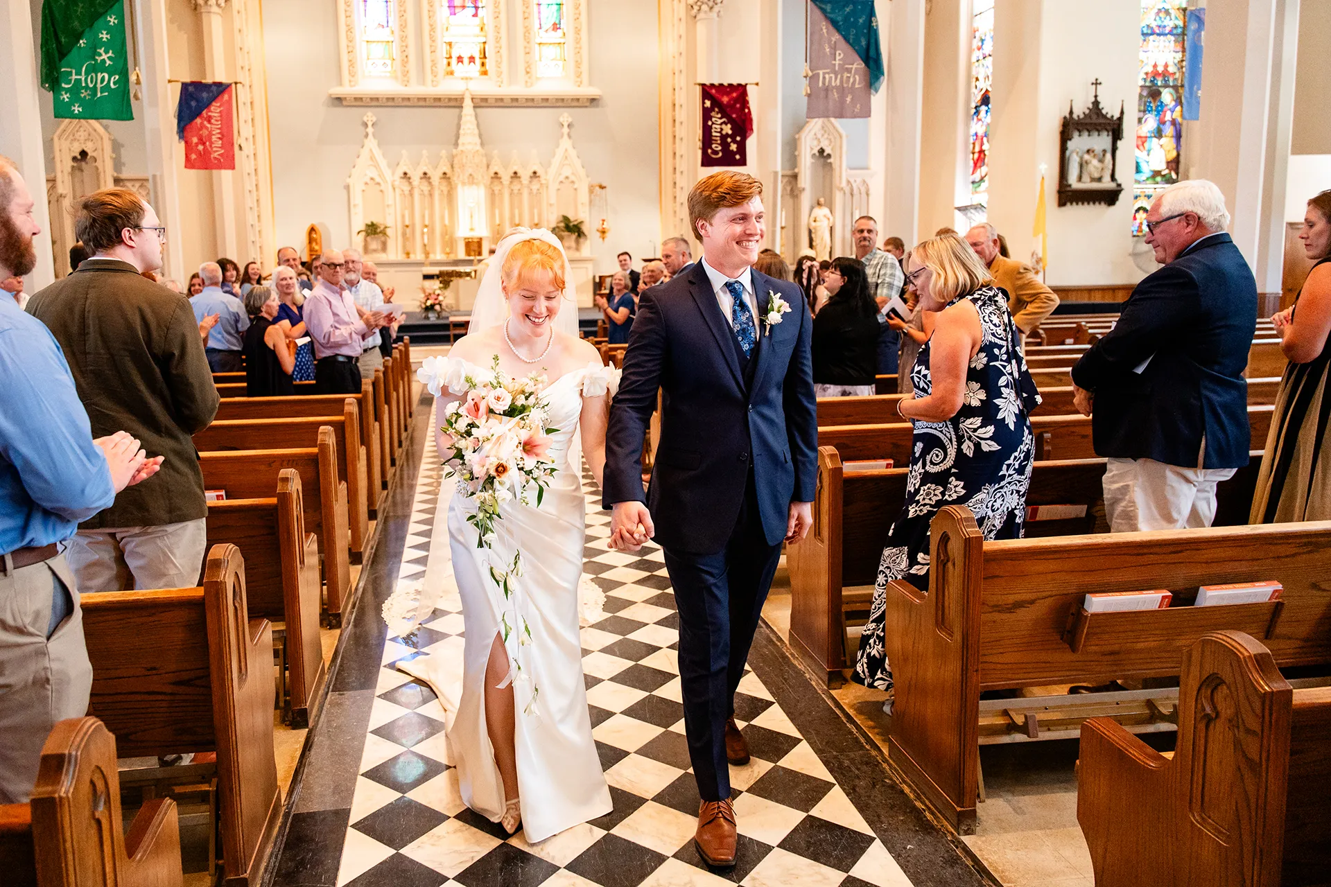 A bride and groom smile as they walk down the aisle after getting married at Saint John's Catholic Church in Bangor, Maine.