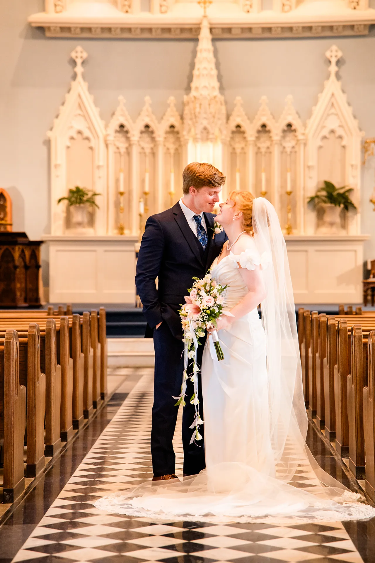A bride and groom smile at each other during wedding portraits at Saint John's Catholic Church in Bangor, Maine.