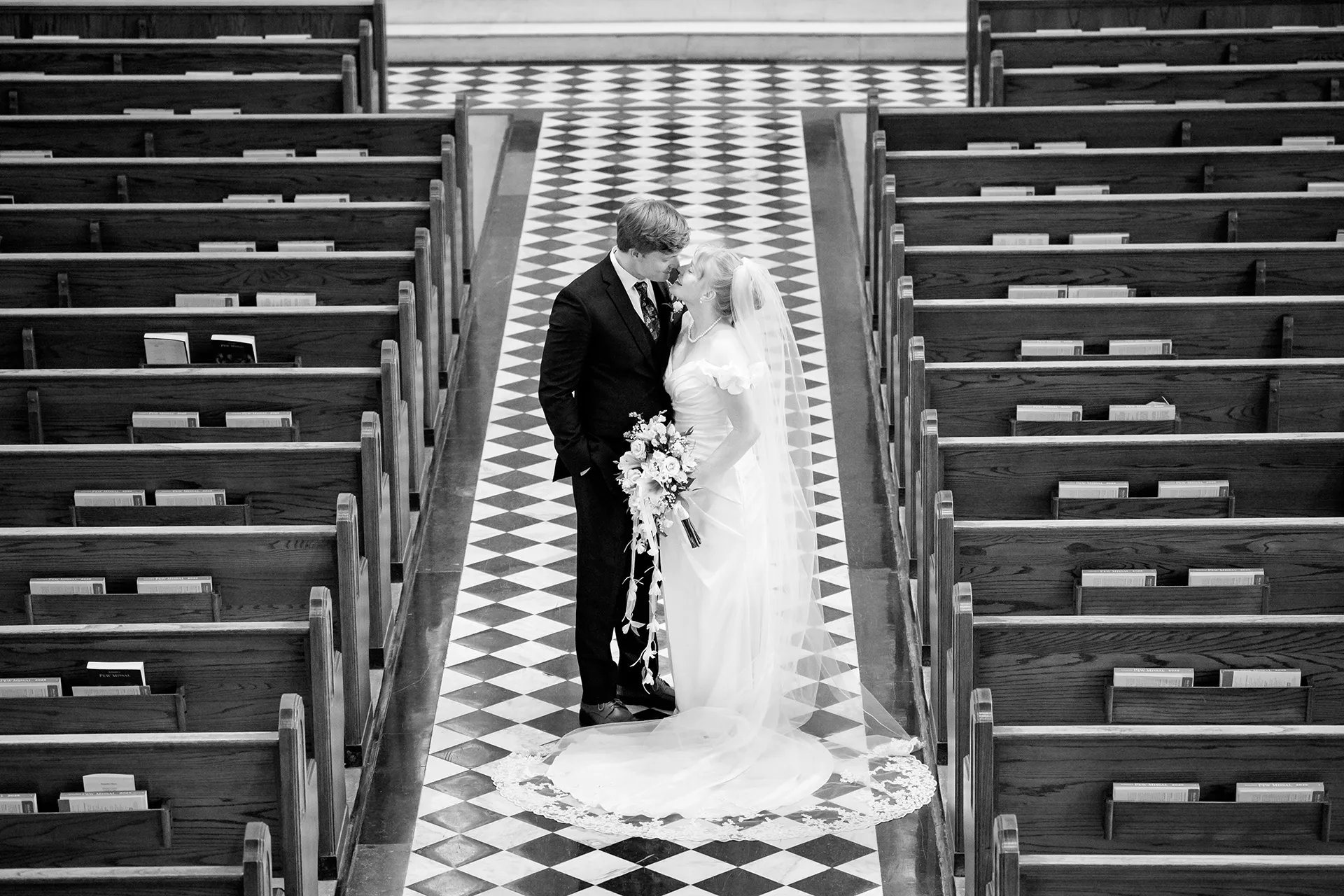 A bride and groom smile at each other as they pose for wedding portraits at Saint John's Catholic Church in Bangor, Maine.